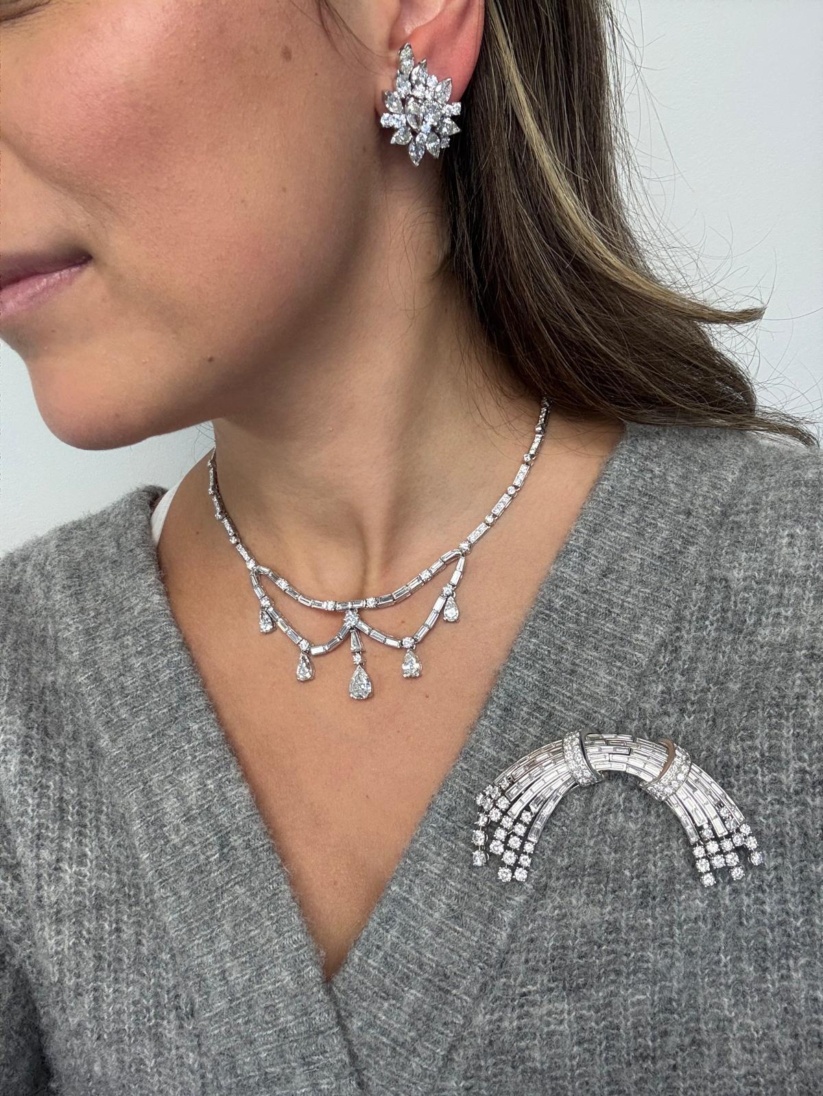 Eine glamour�öse Brosche aus Platin in geschwungener, bandförmiger Form, die eine schillernde Kombination aus runden Brillanten und Diamanten im Baguetteschliff präsentiert. Die Brosche ist mit etwa 7,75 Karat runden Brillanten und 7,95 Karat fein