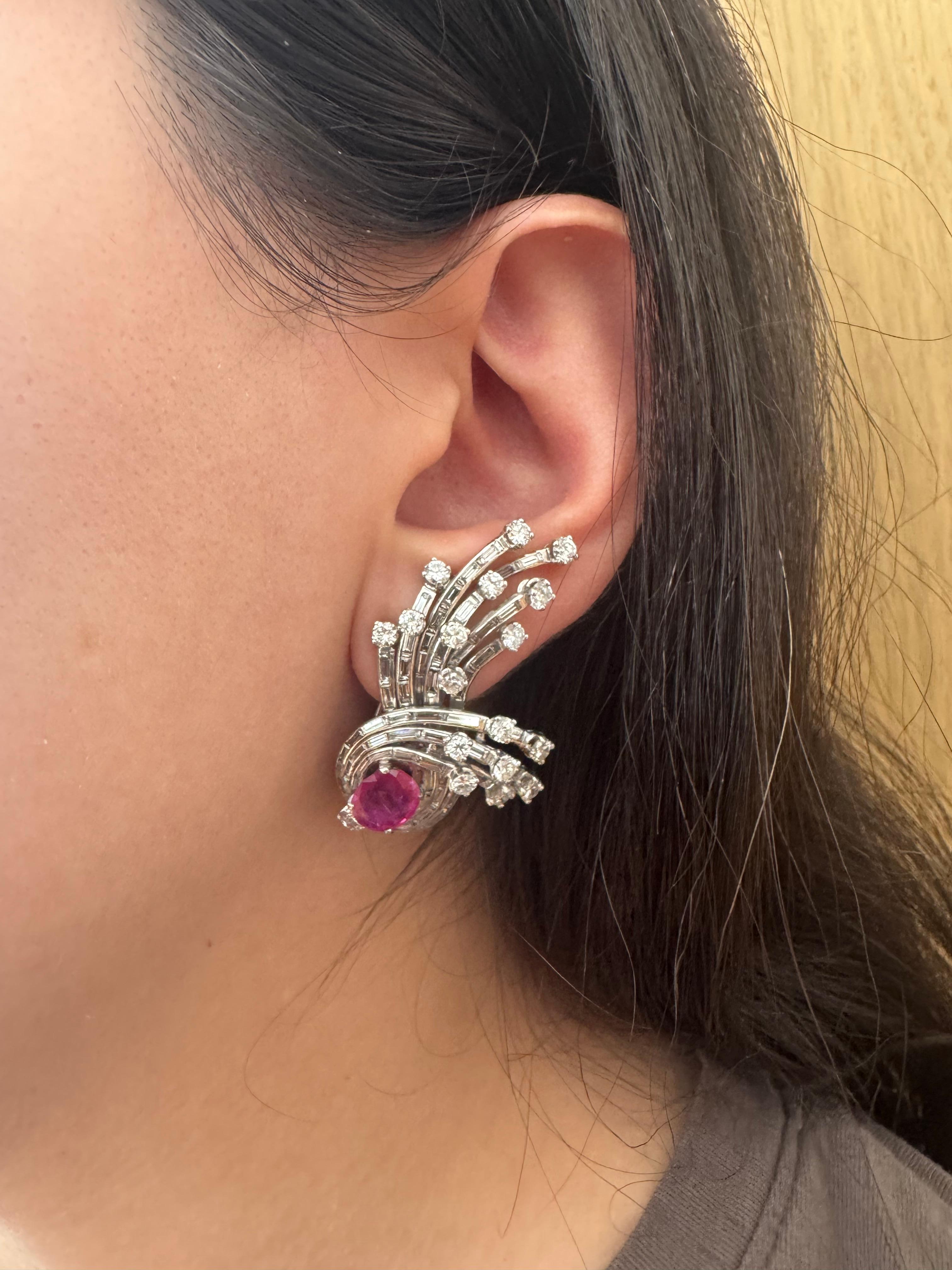 Une étonnante paire de boucles d'oreilles en platine du milieu du siècle mettant en valeur deux rubis éclatants totalisant environ 2,90 carats, chacun étant serti à la base d'un panache de diamants rayonnants. Le design comporte 34 diamants ronds de