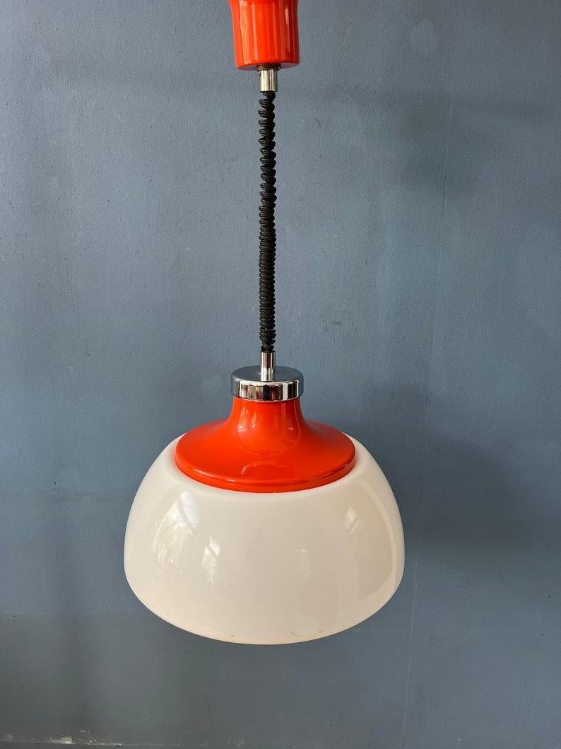 Bellissima lampada dell'era spaziale con paralume in vetro acrilico bianco e cappello superiore in metallo rosso. La combinazione di bianco e rosso crea l'atmosfera caratteristica di questo pezzo. L'altezza della lampada può essere facilmente