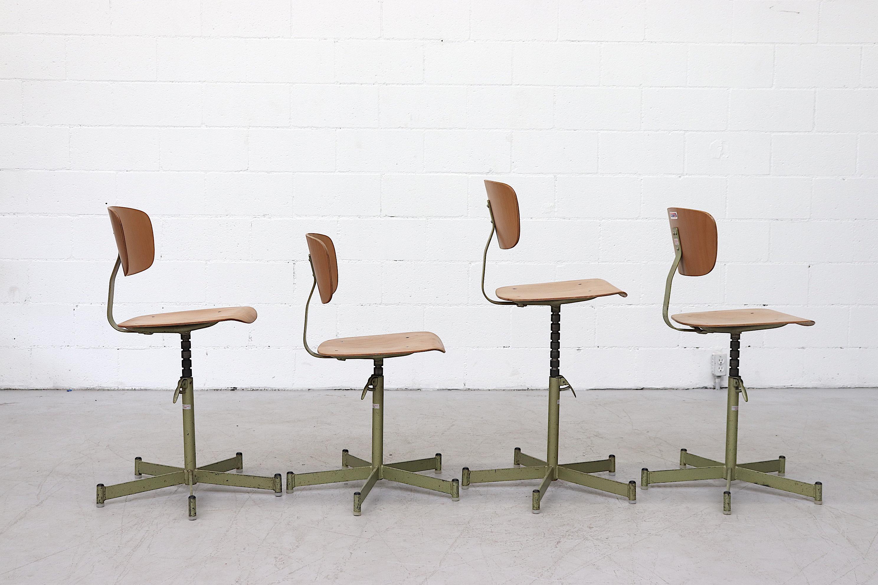 Awesome midcentury plywood drafting stools with moss green enameled tubular metal base and spring triggered height adjustable seat. In original condition with some wear consistent with its use. Priced individually.