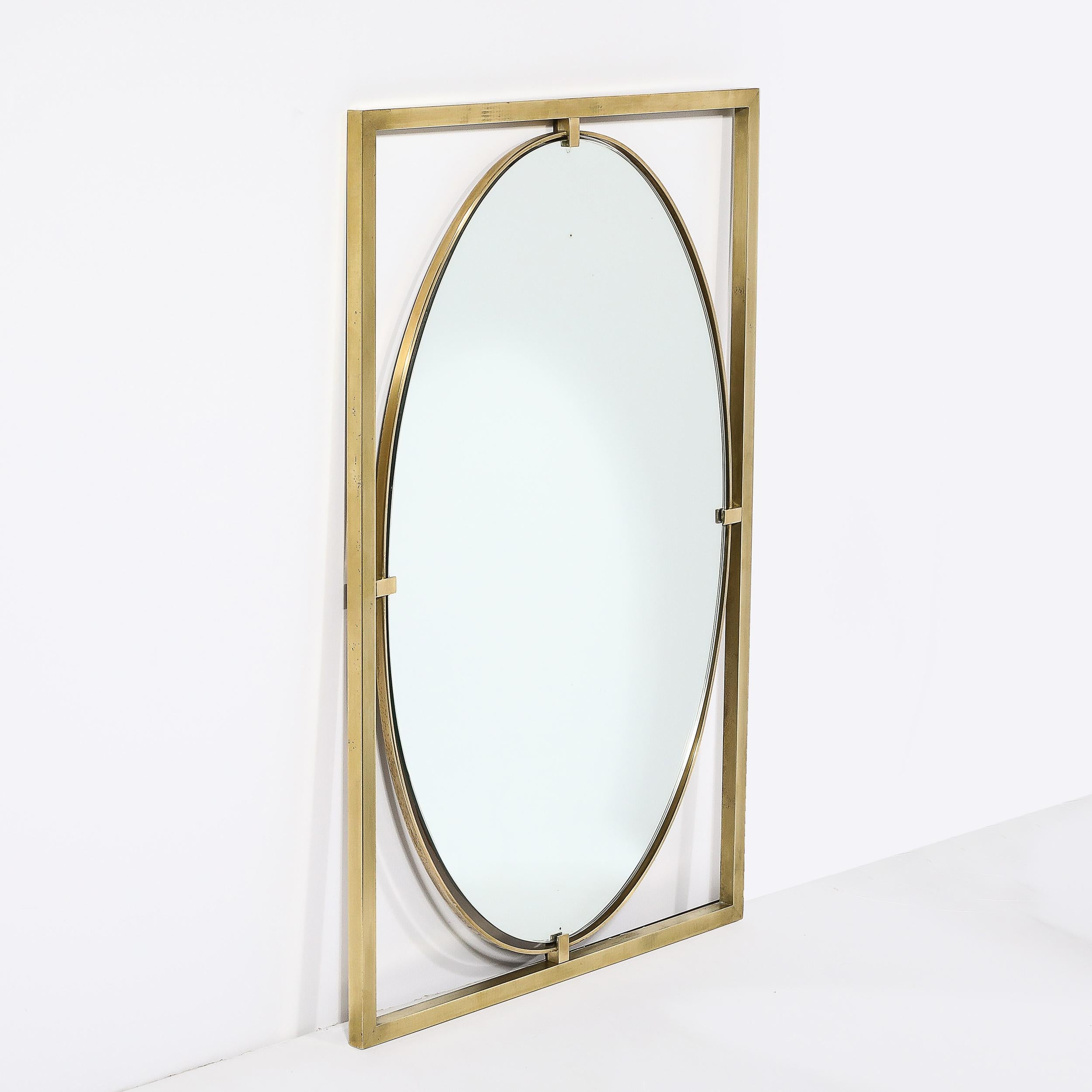 Ce miroir ovale avec cadre ouvert rectiligne en laiton poli, matériellement excellent et bien composé, est une œuvre de John Widdicomb et provient des États-Unis, vers 1960. Le miroir de forme ovale est maintenu par un cadre en laiton avec des