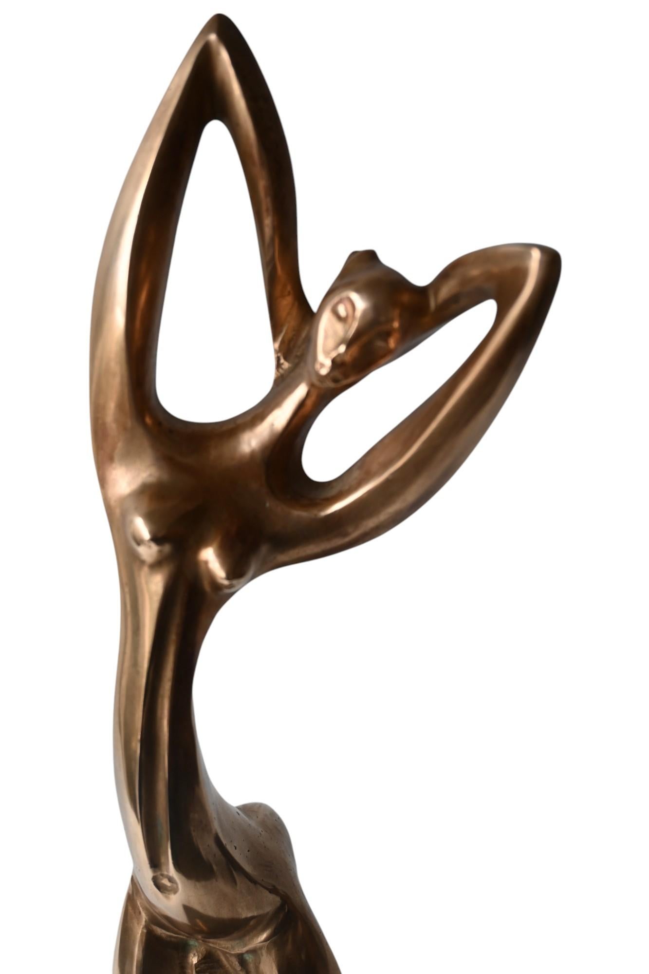 Una statua africanista stilizzata in ottone lucido montata su una base in legno Wengé
Nello stile di Hagenhauer
Ca 1950 
Altezza totale 43 cm, altezza della statua 40 cm, base 14,2 x 14,4 cm.