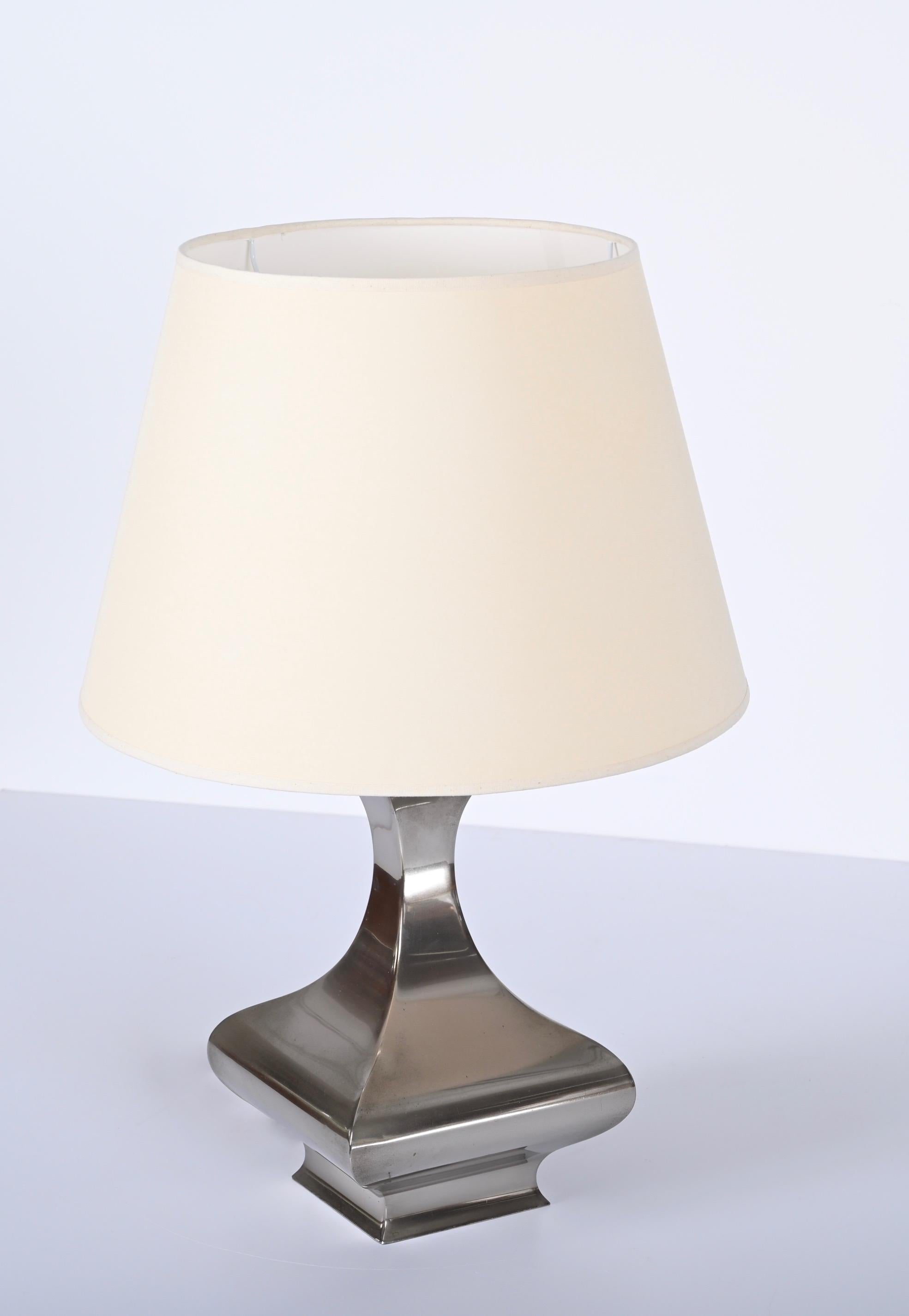 Stunning table lamp in polished stainless steel designed by Maria Pergay, France 1970s.

This rare lamp features a beautiful square curved base with a concave neck and a rounded white fabric lampshade. Any type of light bulb with an E27 screw base