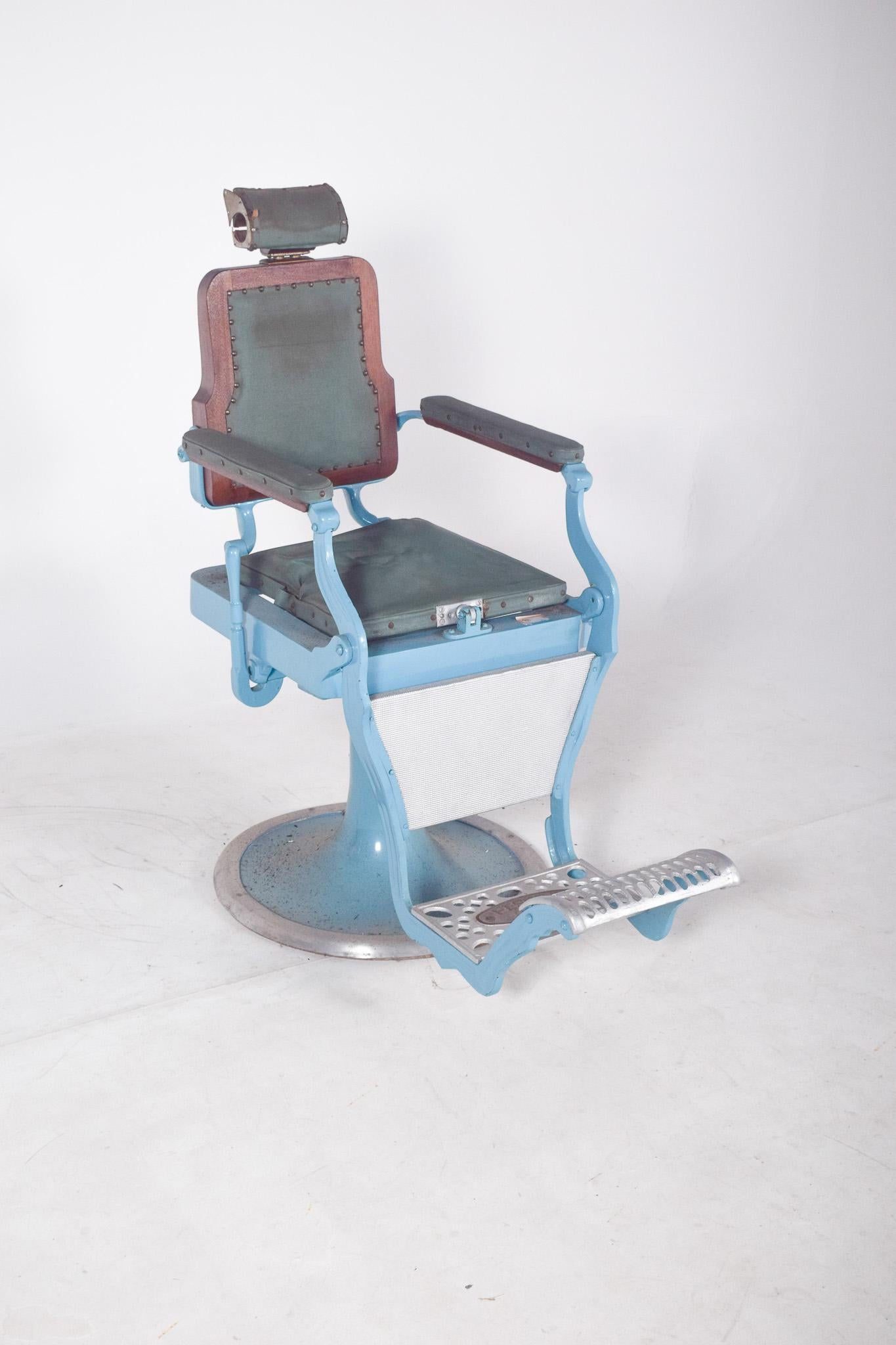 Chaise de barbier. Fabriqué en métal émaillé bleu clair et recouvert de cuir synthétique foncé à rayures. La base circulaire robuste assure la stabilité de la structure, typique des modèles hydrauliques classiques, bien que ce modèle ne semble pas
