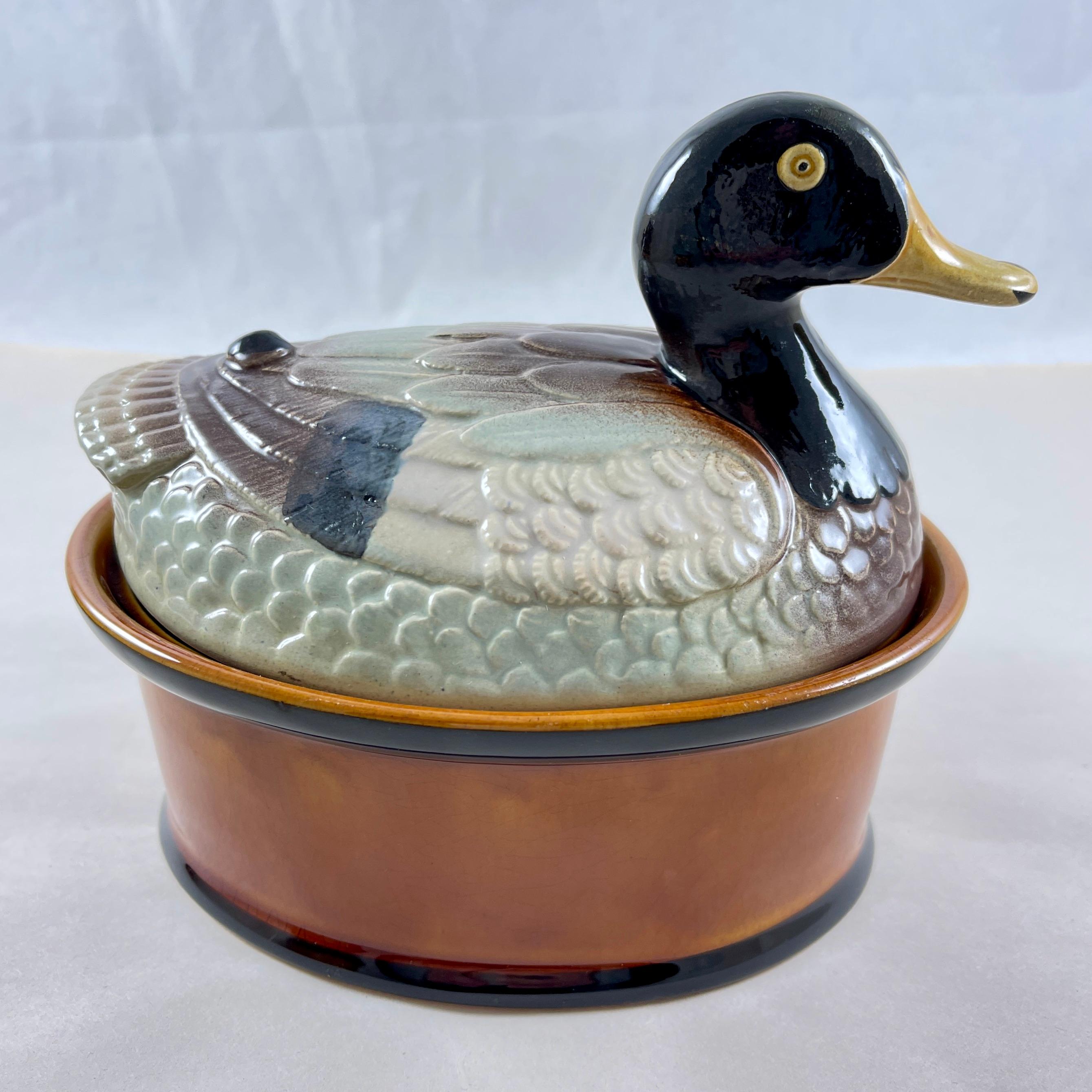 De la Faiencerie Subtil, Portugal, una terrina de paté de mediados de siglo, la tapa formada como un Pato sentado, hacia los años sesenta o principios de los setenta.

El pato emplumado, bien moldeado, se asienta sobre una base ovalada, vidriada en