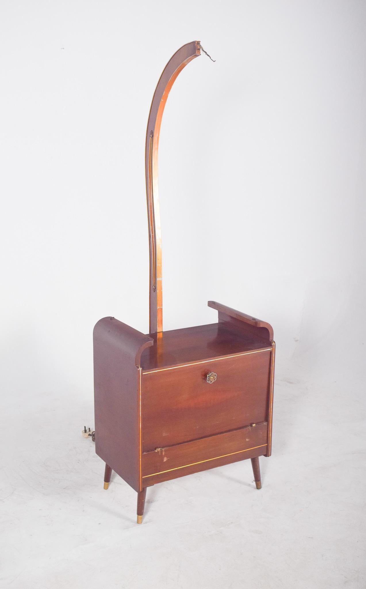 Kleine Bar aus den 50er Jahren. Aus hellem Holz, mit einer lackierten Oberfläche, die die natürlichen Maserungen hervorhebt. Es ist ein kompaktes Möbelstück und steht auf vier spitz zulaufenden, leicht schrägen Beinen mit vergoldeten Metallspitzen.