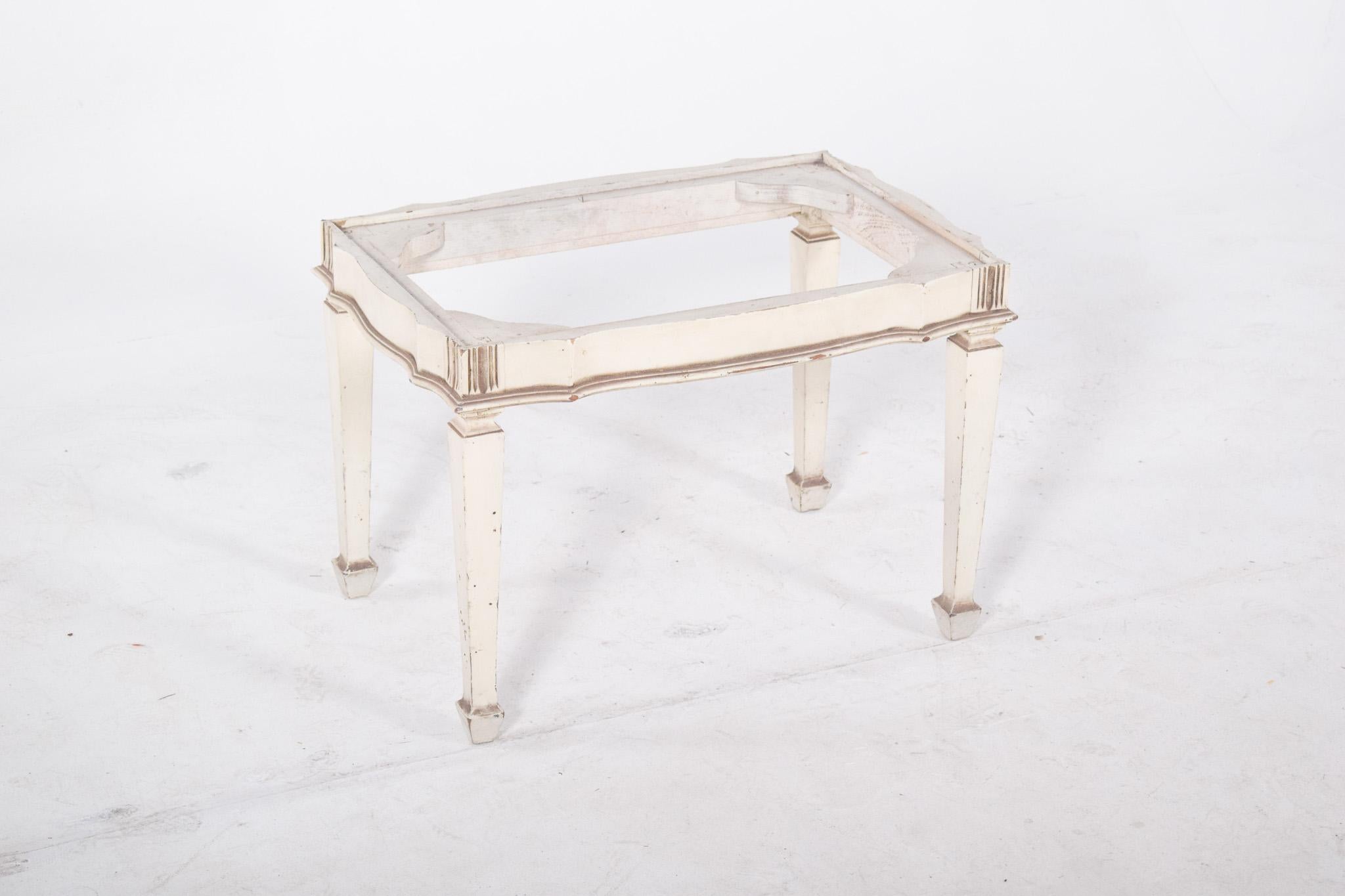 Coffee table painted white. With details in aged gold, it evokes a neoclassical style. With its tall, tapered legs, it has a delicate cut-out frame that runs along the entire perimeter of the skirt, giving it elegance and lightness. The discreet