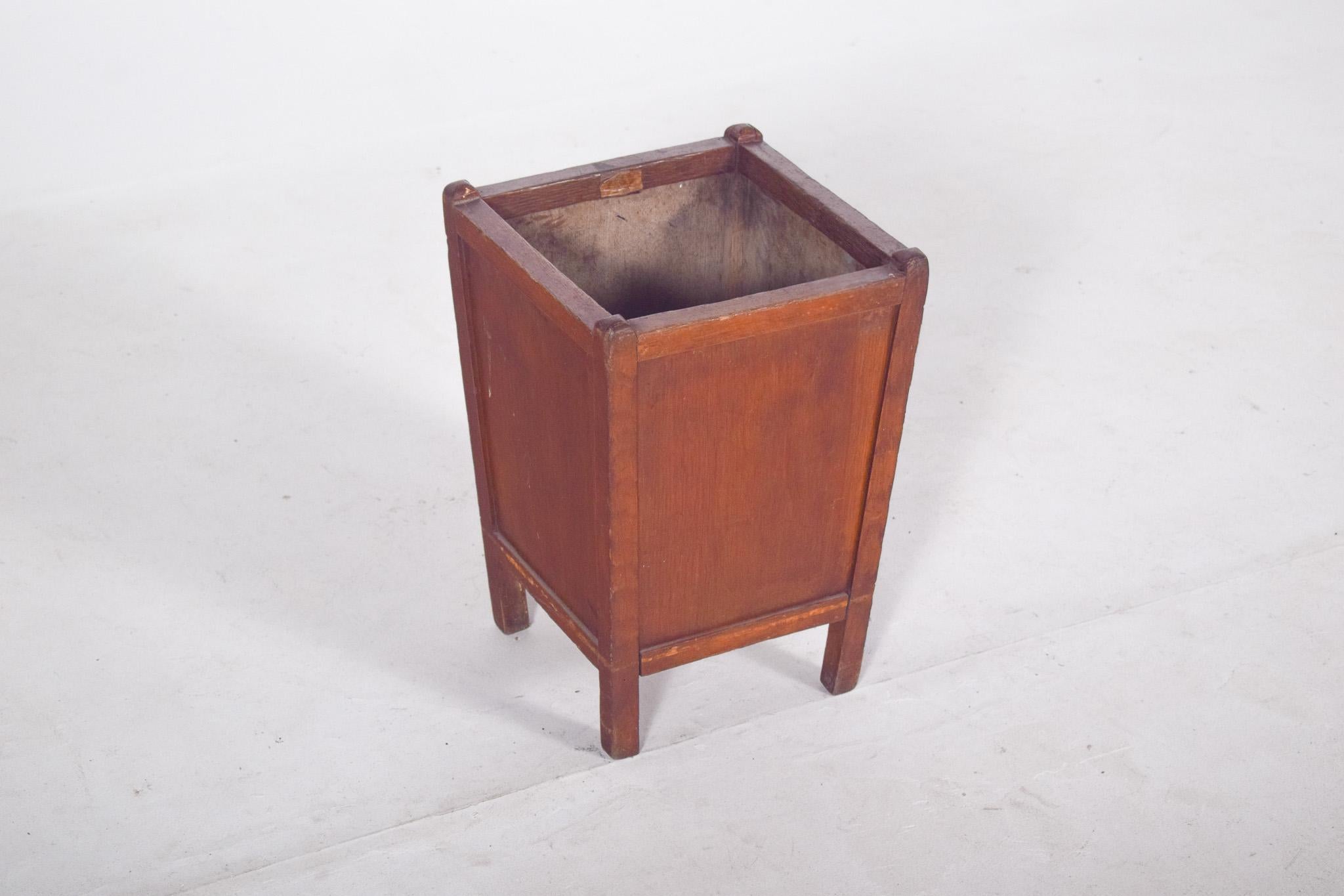 Cestino in legno. Con una forma quadrangolare e linee semplici, è un oggetto funzionale che riflette lo stile utilitaristico dei decenni passati. I lati sono lisci, con angoli delicatamente arrotondati, e i piedi sono un'estensione delle strutture