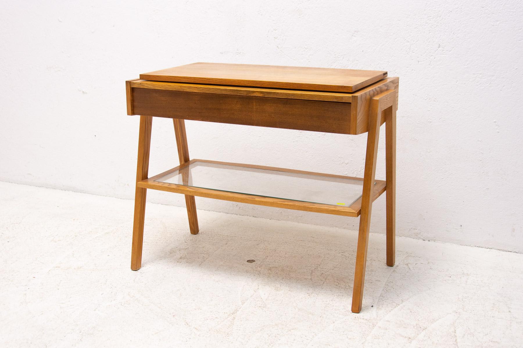 Mid-century positioning TV table. It has an ash wood structure, one drawer, revolving top and a glass storage top in the middle.

In good Vintage condition, shows slight signs of age and using ( minor fading on the top and small chip).

