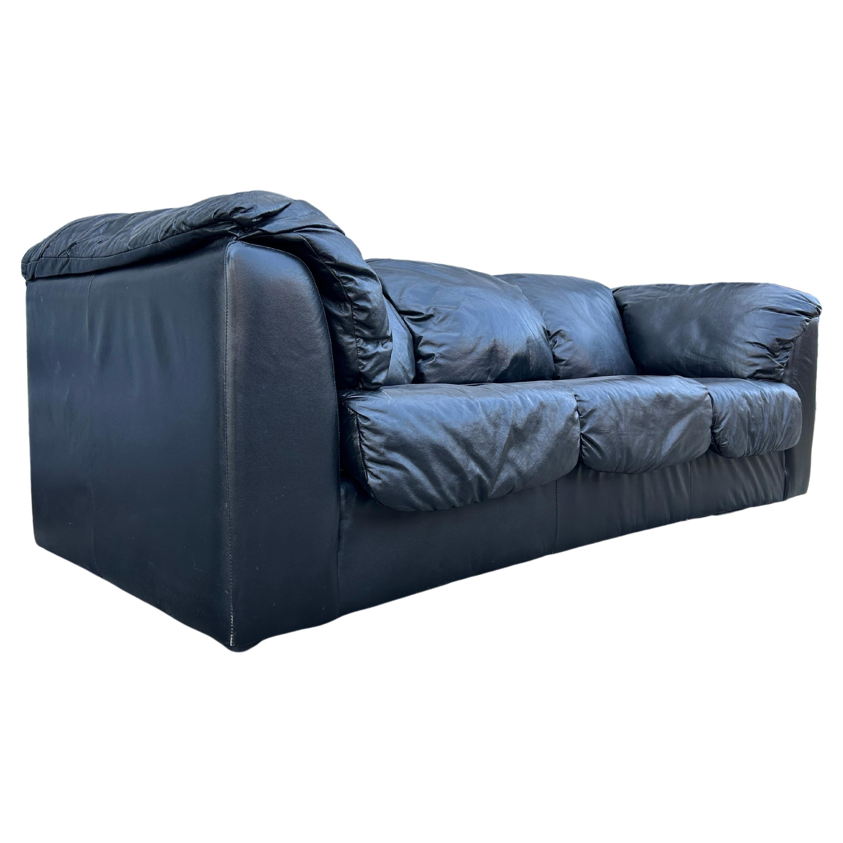 Clean midcentury post modern 3 seat black leather puffy sofa circa 1980. This sofa is a time capsule from the 1980s/1990s with puffy side arms and back cushions and 3 lower cushions. The sofa is all original in very nice condition. Very comfortable