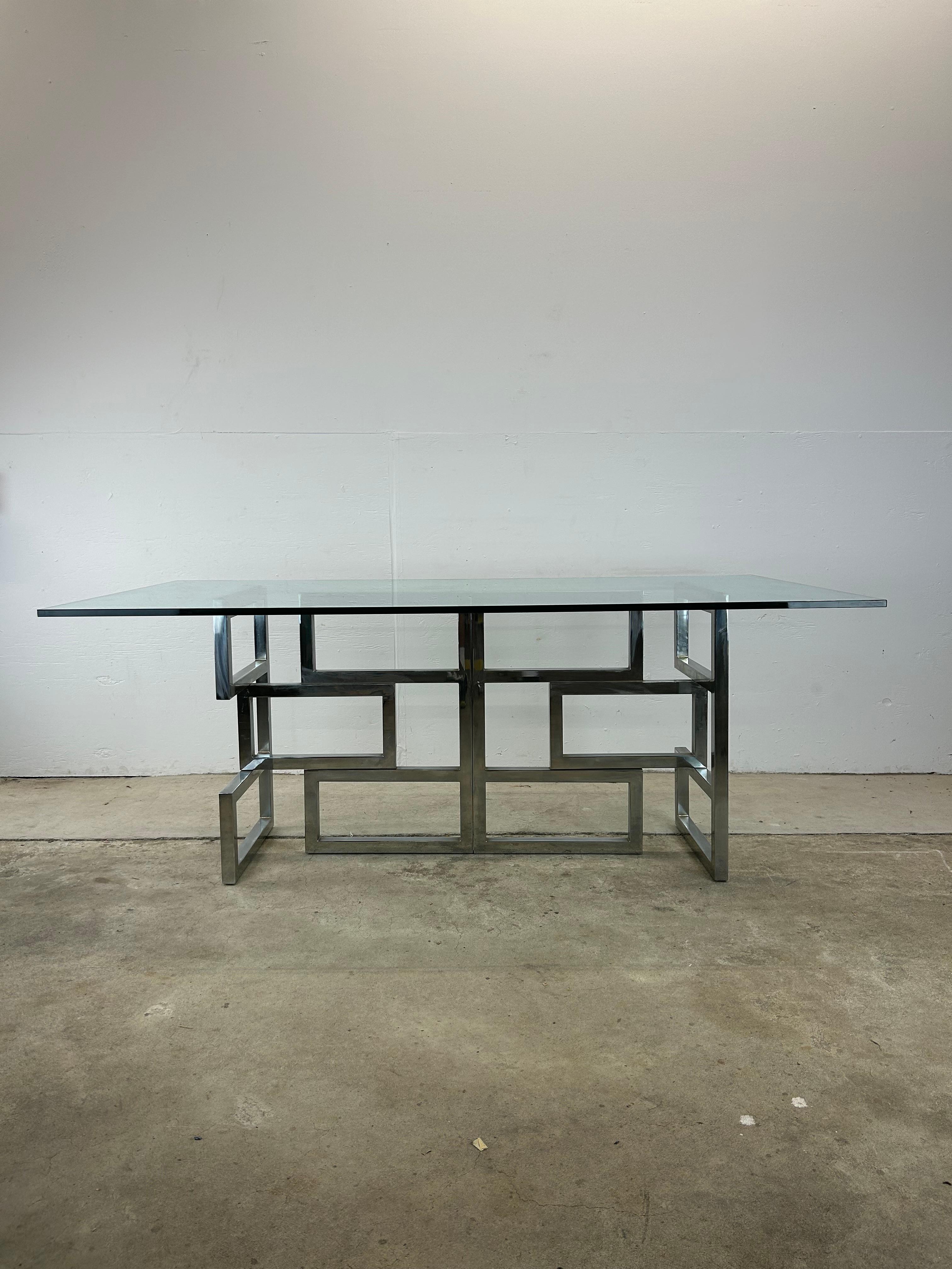 This mid century post-modern dining table features chrome base with geometric design and thick glass table top.

Complimentary post-modern dining chairs available separately. 

Dimensions: 72w 39d 29h 38 knee h

Condition: Chrome base is in