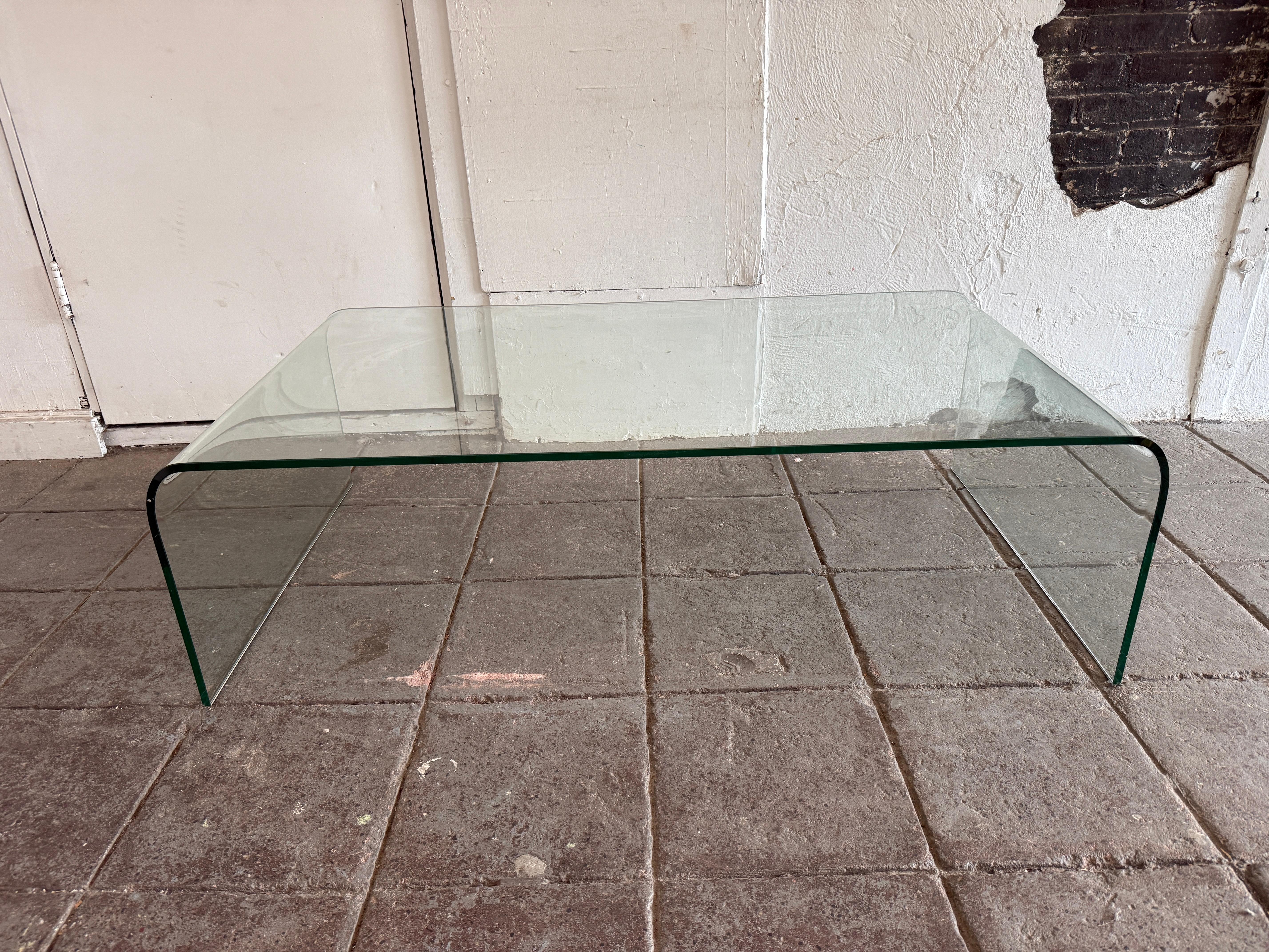 Post modern coffee table with a waterfall top. Glass is very clean no chips or major scratches. May have light normal use wear to surface. Rounded polished edges. Annealed glass has blue hue. Made in Italy. Located in Brooklyn NYC. 

Message us for