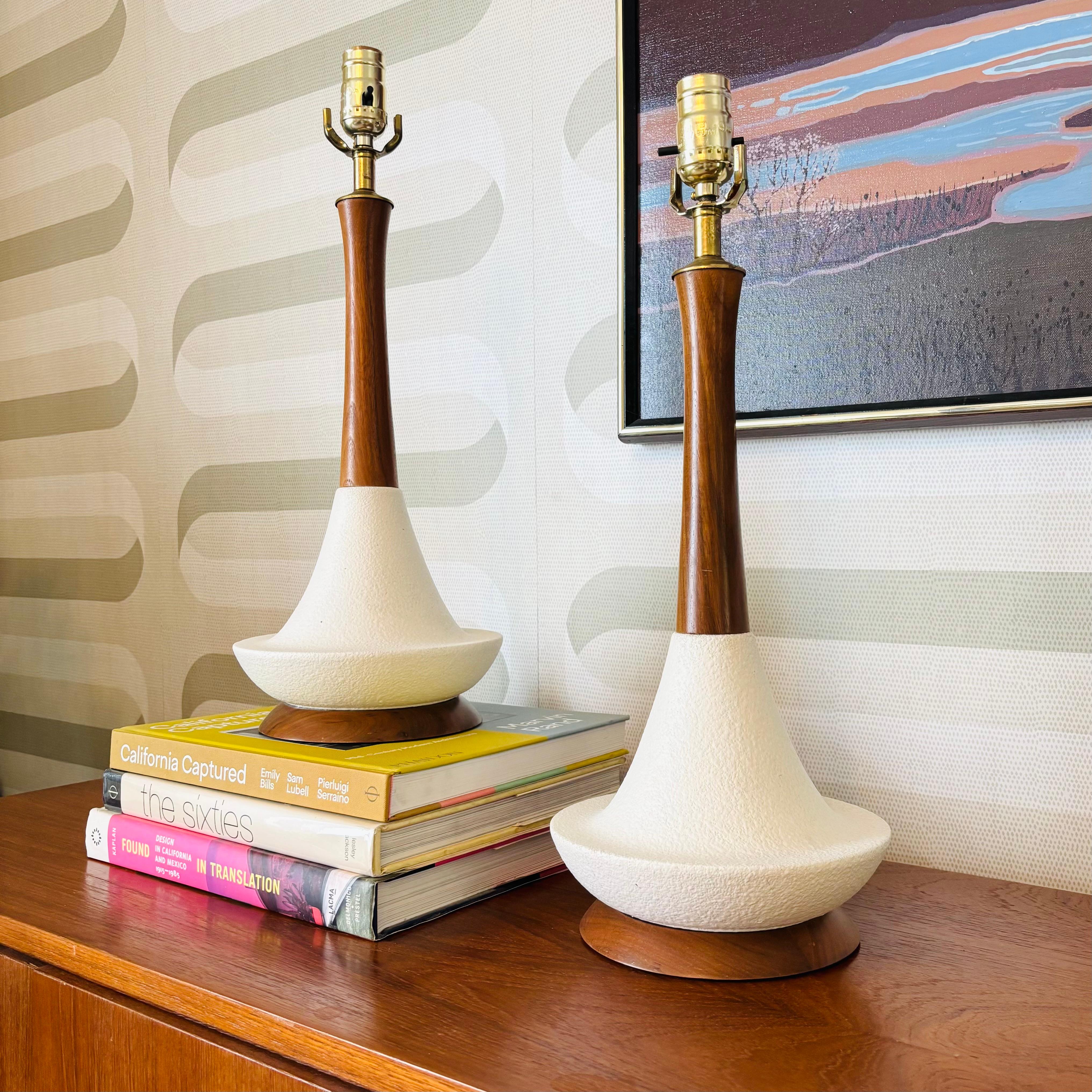 A pair of matching mid century table lamps. Each lamp features a pottery base and turned wood neck and base. Lovely texture to the ceramic with a matte white glaze. Recently rewired and working perfectly.

