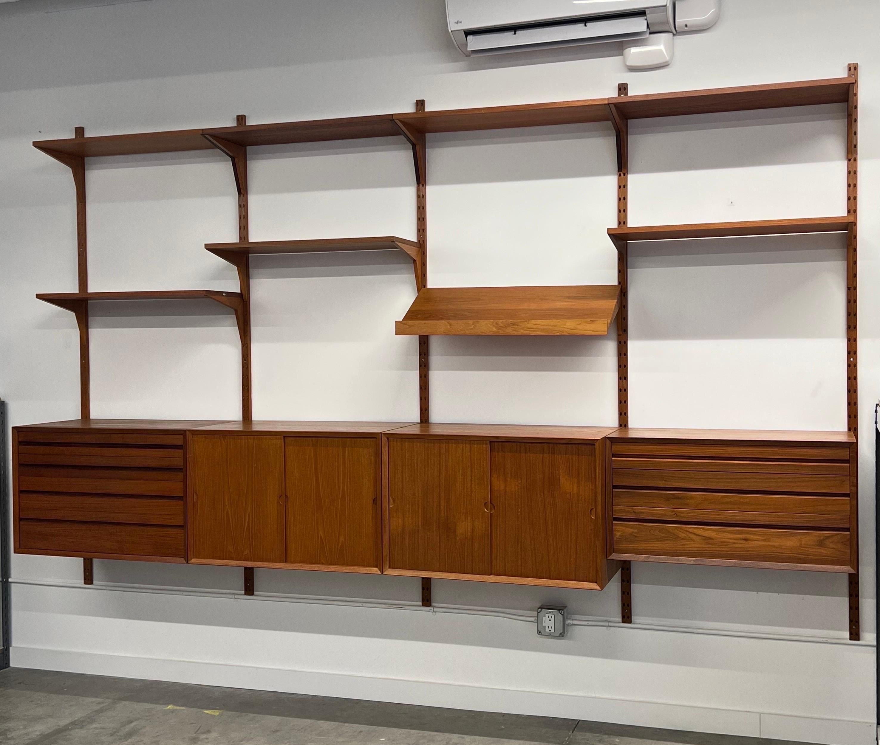 Mid-century iconic wall unit designed by Poul Cadovius, Denmark or often referred to as the “Cado” wall unit. This configuration features four cases, one magazine rack, and seven open shelves. The four-bay is made from teak wood with impressive