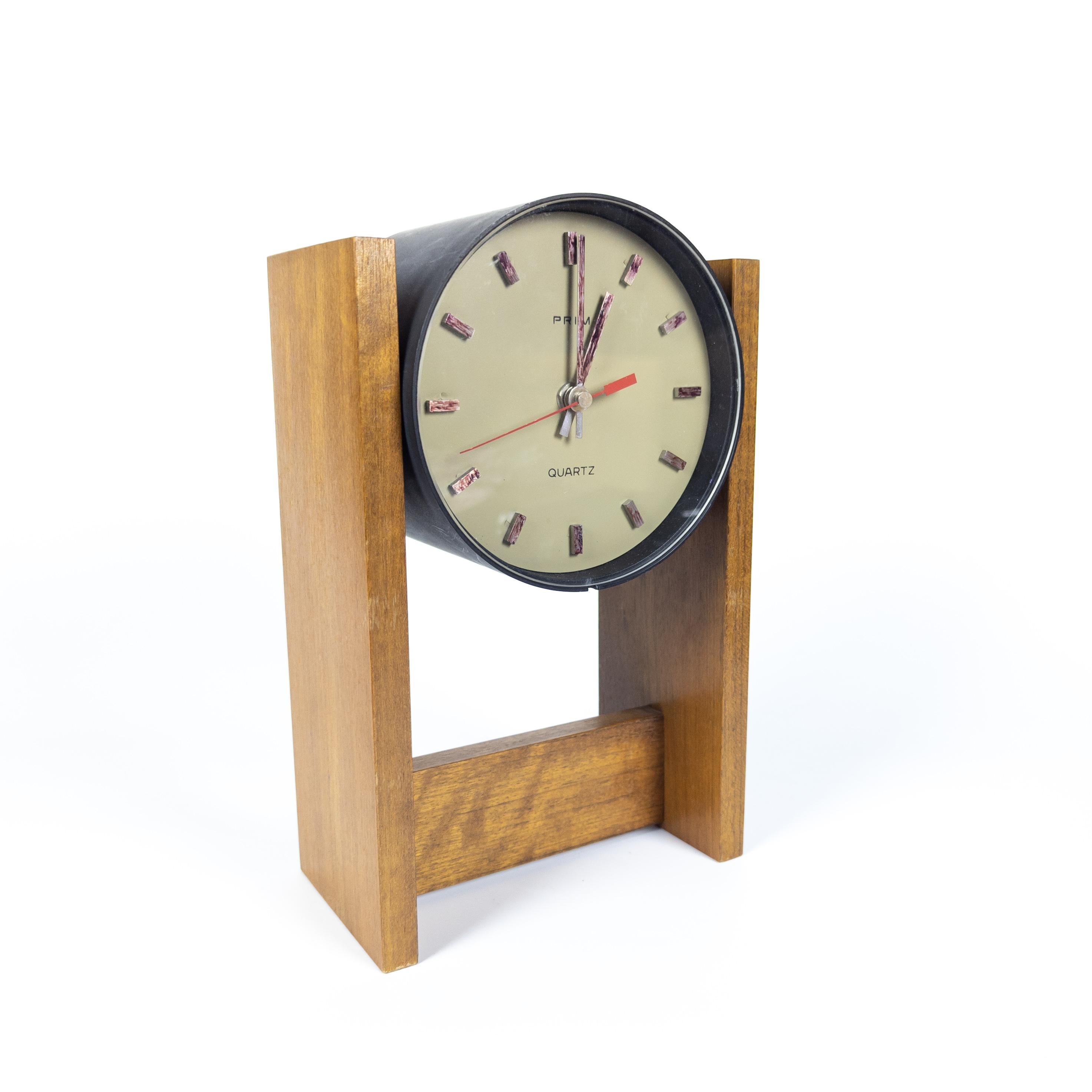 Arm watches and wall clocks Prim have made a name for themselves in the world. Round plastic clock with a simple dial and a red second hand are fitted in a wooden form which can be easily hanged or used as desk clock. The clock is fully functional