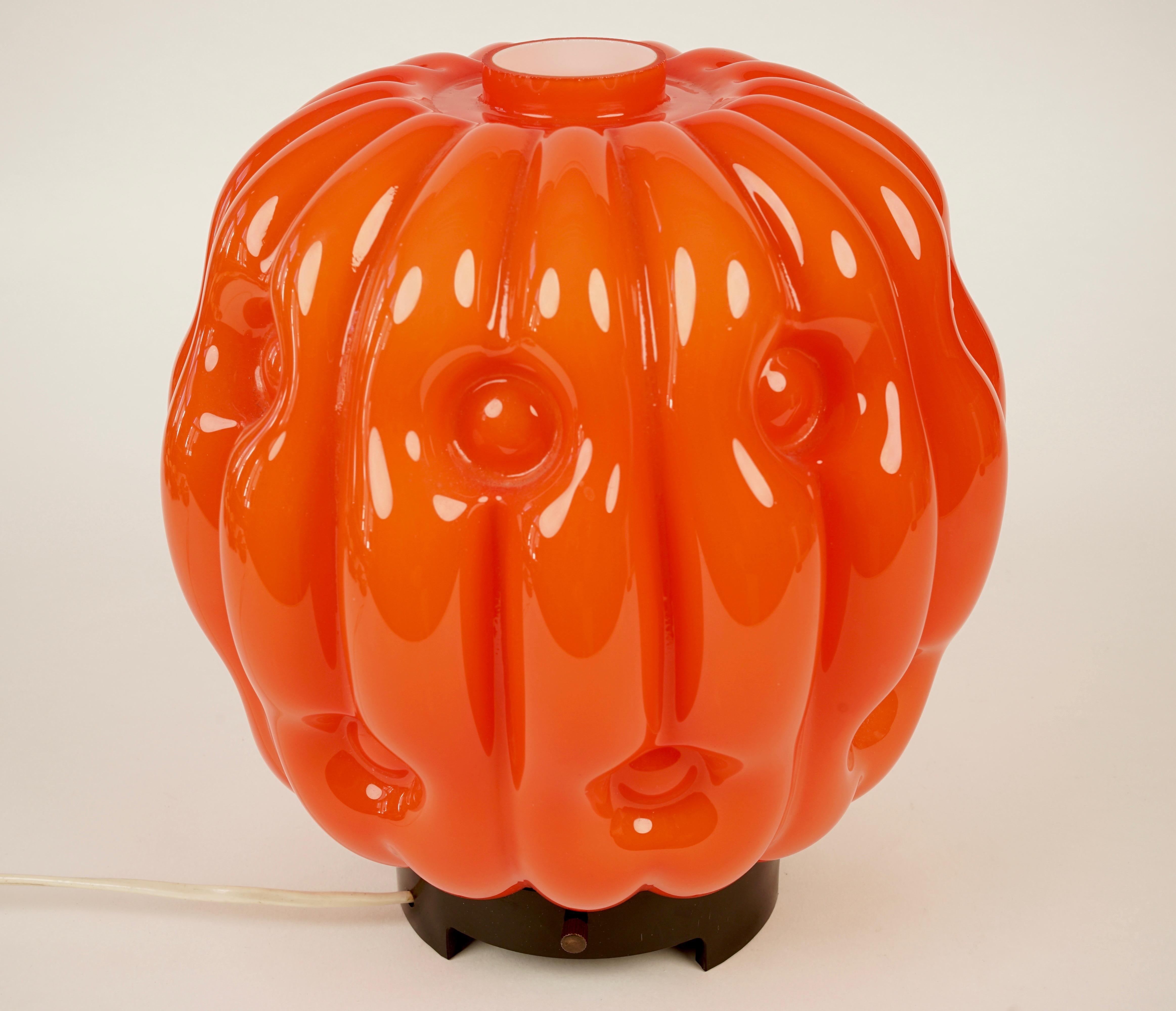 The stylised opaline glass pumpkin's lamp is from the 1960s.
The glass is attached to a bakelite base with three set screws there is a tiny chip to be seen in the last photo.
The light emitted is warm and soft.
 