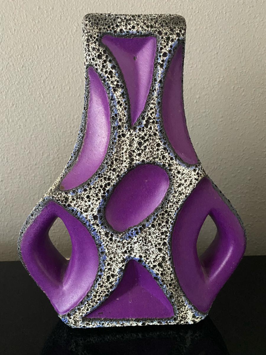 A Roth Keramik double-handled vase, with blue outlined white and black lava and is only found with purple glaze. These vases are very sought after and especially in the colors yellow or purple.
This iconic form has give the nickname the 