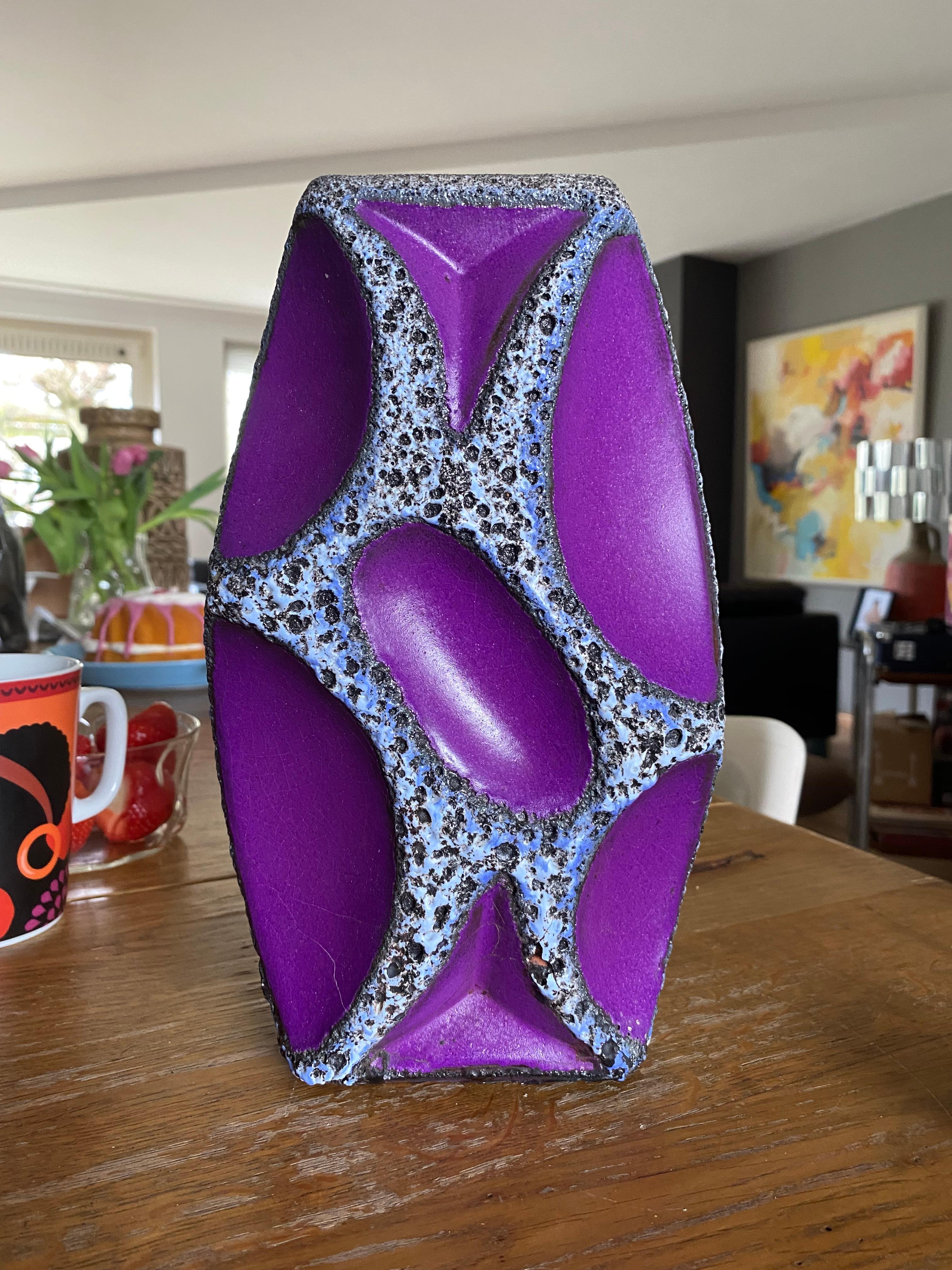Un vase en céramique de Whiting, avec une lave aux contours bleus, blancs et noirs et une glaçure violette. Ces vases sont très recherchés, surtout dans les couleurs jaune et violet.

