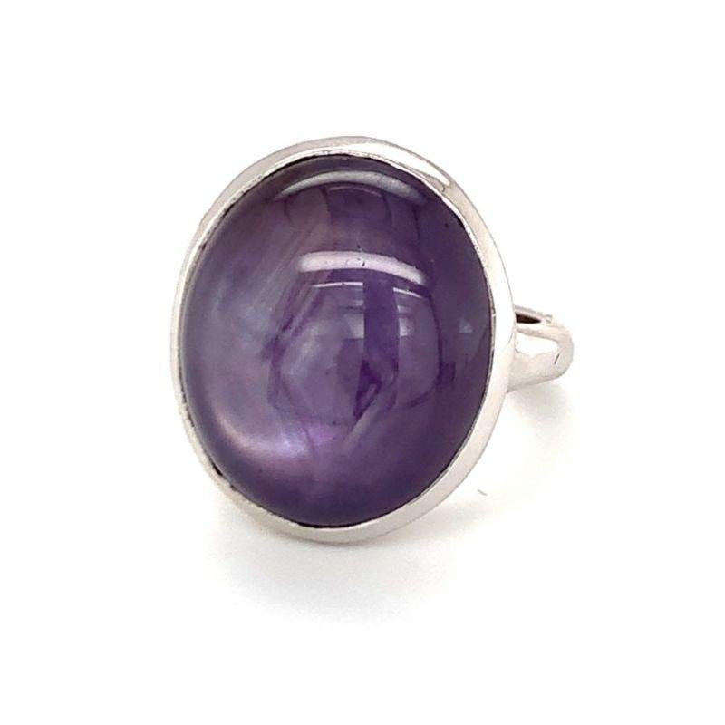 One purple star sapphire 18K white gold ring featuring one oval cabochon purple star sapphire totaling 34 ct. with medium-strong asterism (star display). Circa 1950s.

Mesmerizing, magical, moody.

Additional information:
Metal: 18K white