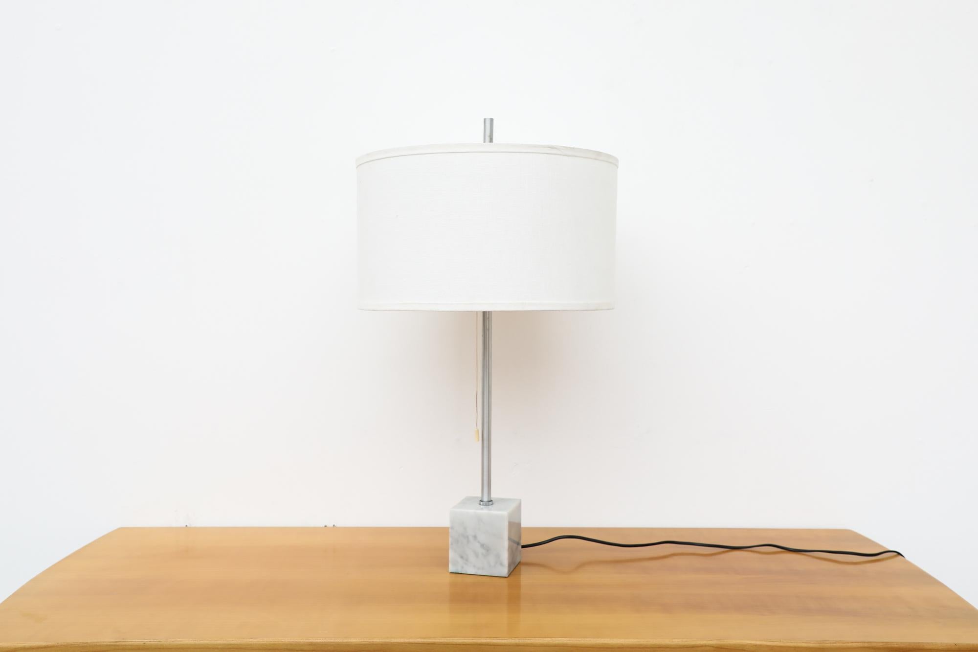 Mid-Century table lamp by RAAK with square marble base, chrome stem and new white linen shade. The lamp has two sockets for medium base light bulbs. In otherwise original condition with visible wear consistent with its age and use.