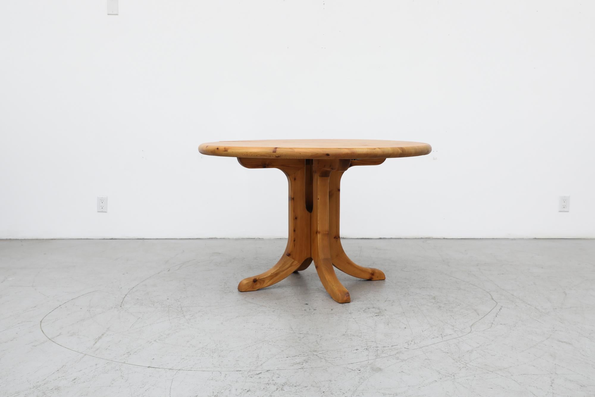 Mid-Century Rainer Daumiller Inspired round solid pine dining table with an extension leaf and pedestal base. The base splits from a single pedestal support to a double pedestal support. It is lightly refinished with some visible wear consistent