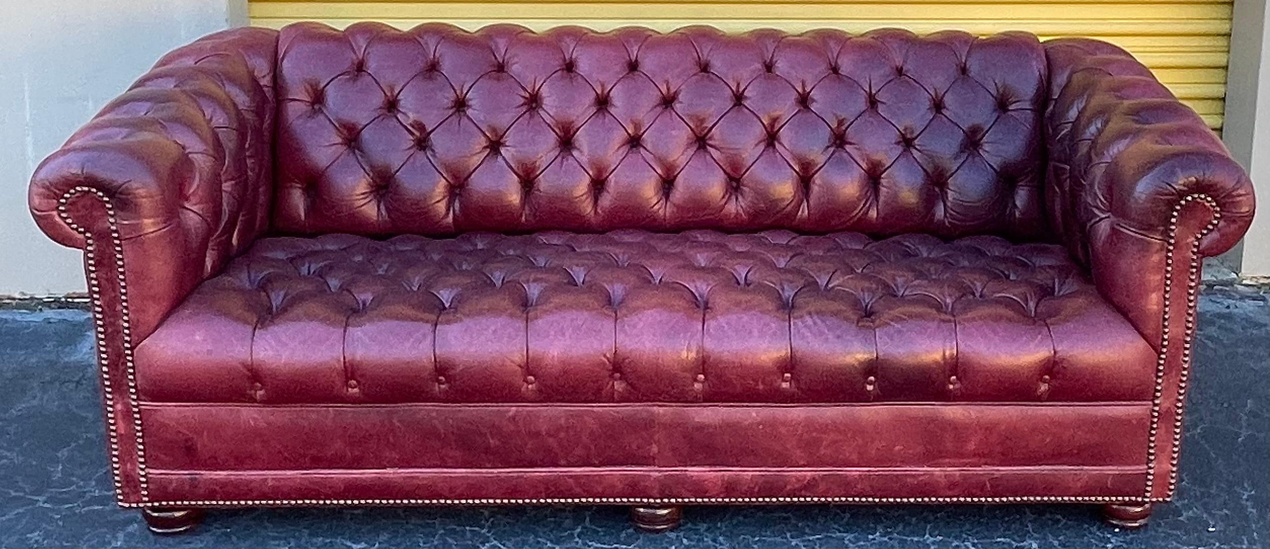 I love this color! It is a mid-century tufted leather chesterfield sofa hand crafted in the United States. It has turned mahogany feet. It has general age wear.