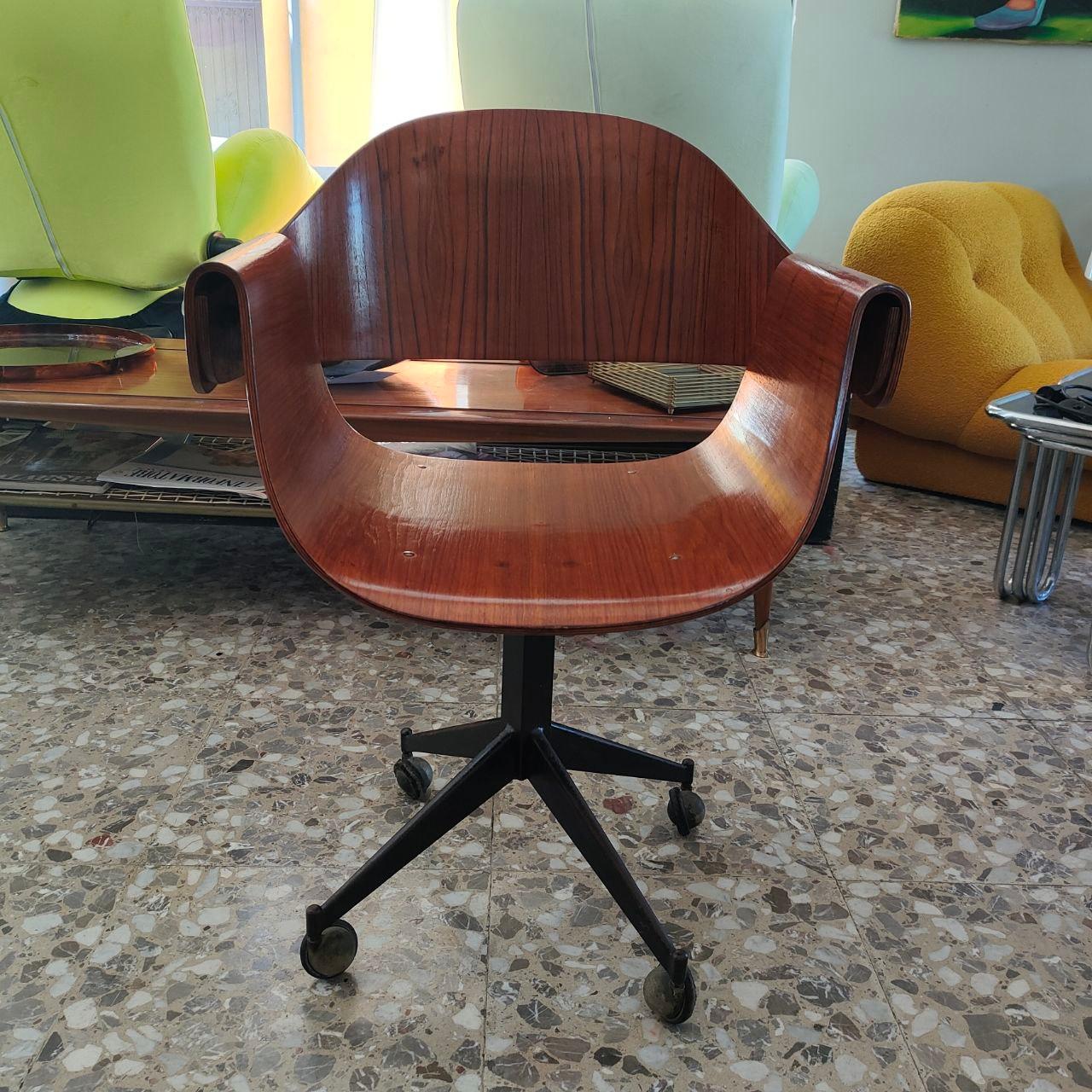 A remarkable example of mid-century Italian office seating, this “Genziana” chair was designed by Carlo Ratti in 1958 for Industria Legni Curvati Lissone. Its sleek, curved plywood shell offers ergonomic comfort, while the central metal column with