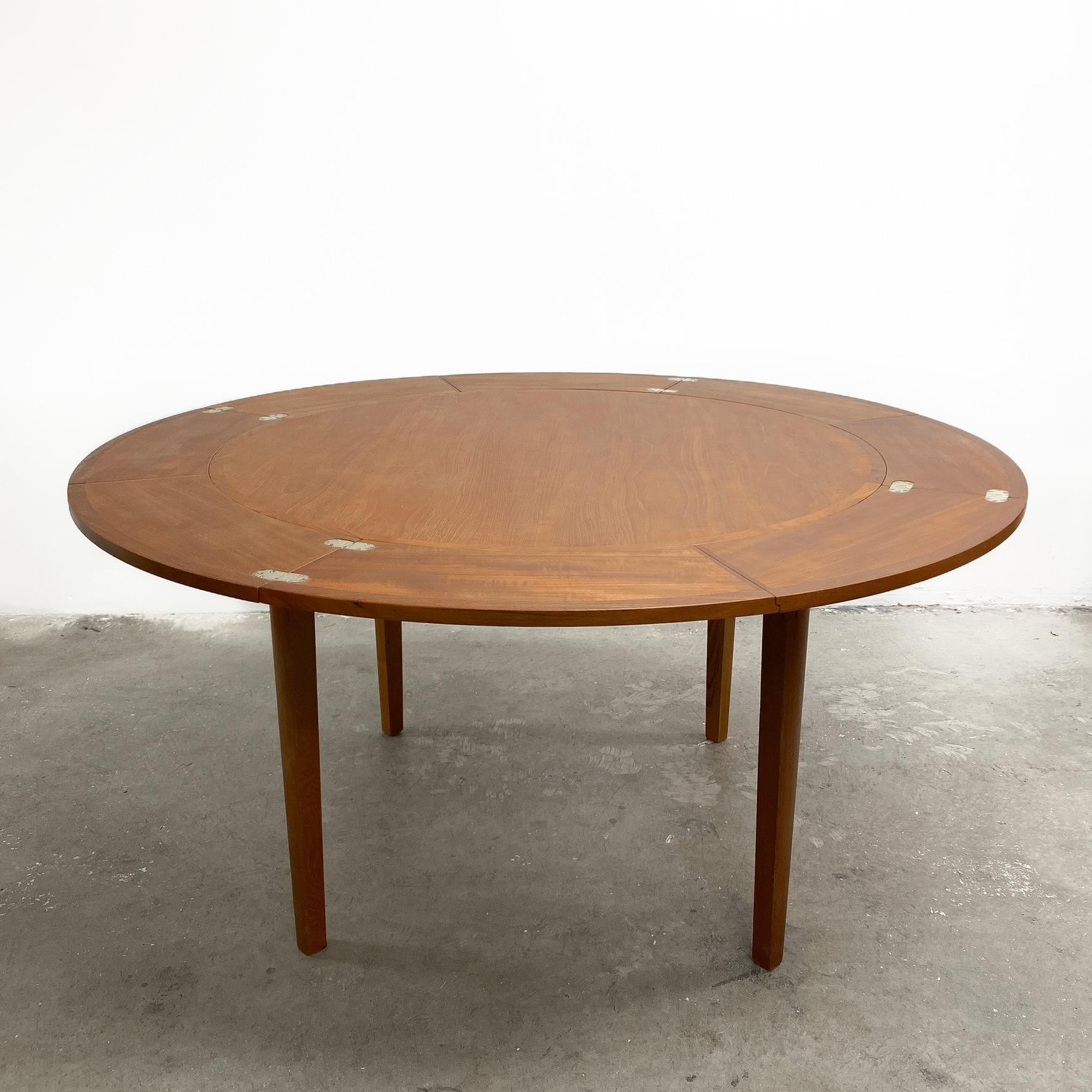 Mid Century rare circular to circular flip-flap TH Brown Extension Dining Table. It retains its original circular metal badge to the underside.

This extendable dining table has four leaves which pull out and flip over to rest on each other to form