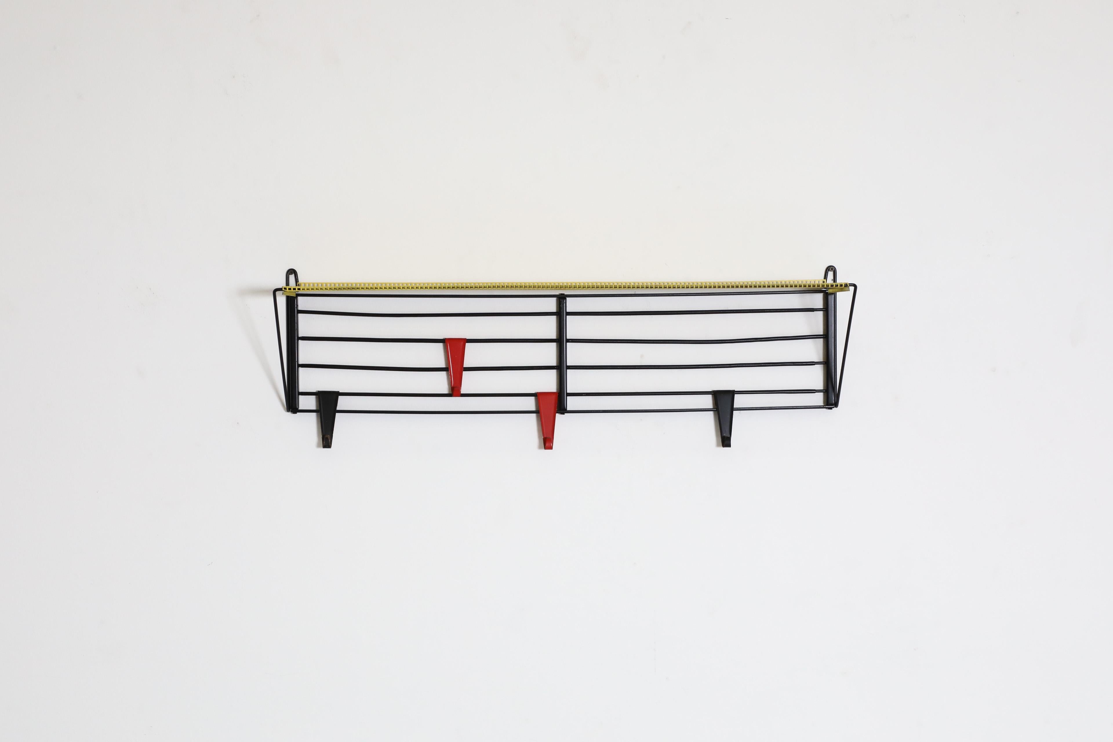 Raro appendiabiti da parete di Pilastro. Uno scaffale industriale degli anni '60 con un ripiano superiore in metallo smaltato giallo perforato su una struttura in metallo smaltato nero. Questo pezzo combina funzionalità e stile grazie a linee decise