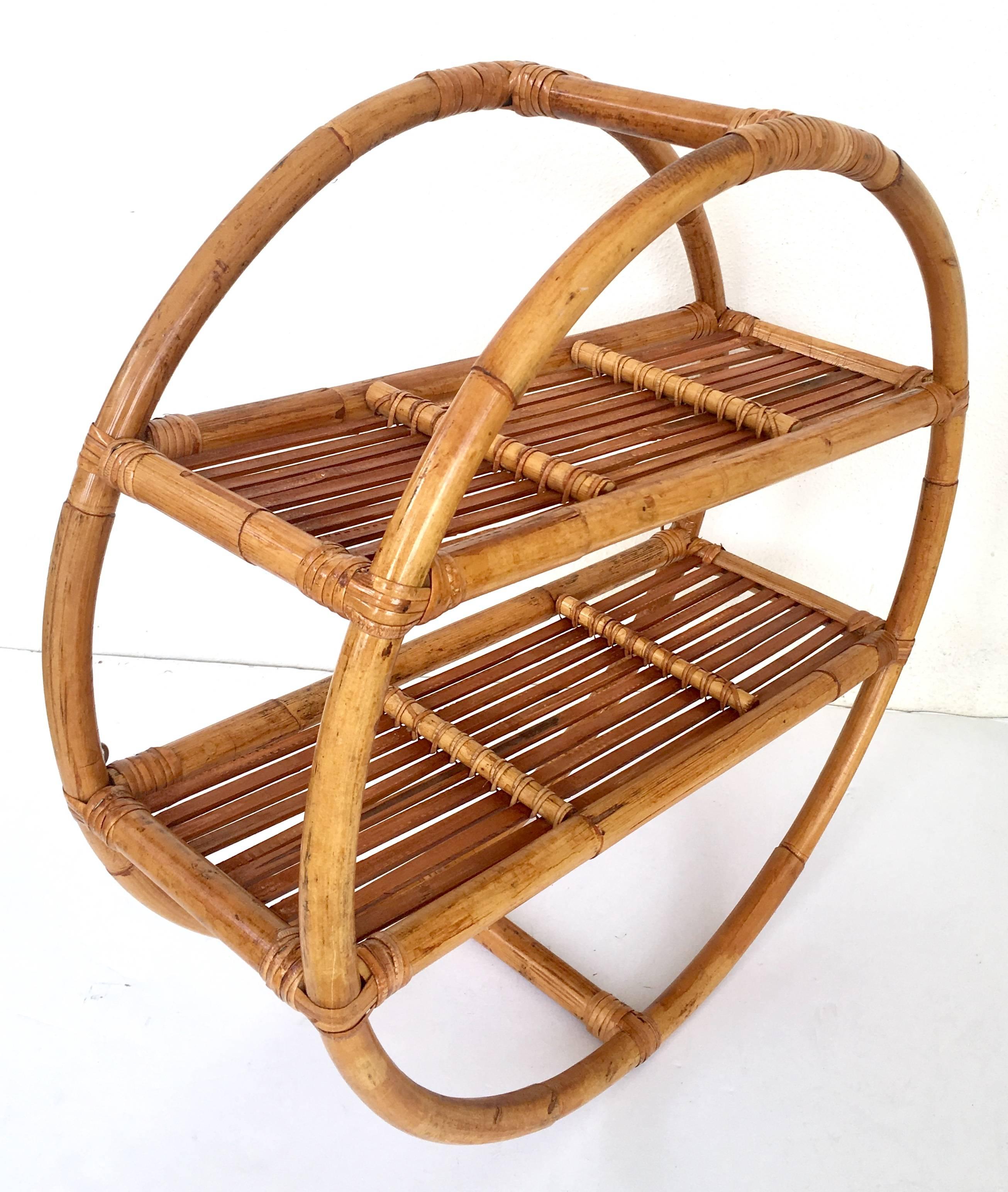 Art Deco bent rattan and wicker round wall-mounted shelf display. This rare and coveted two shelf, round wall-mounted shelf is fabricated of bent rattan and features two existing steel mounted hooks and is ready to hang. Each shelf is approximately,