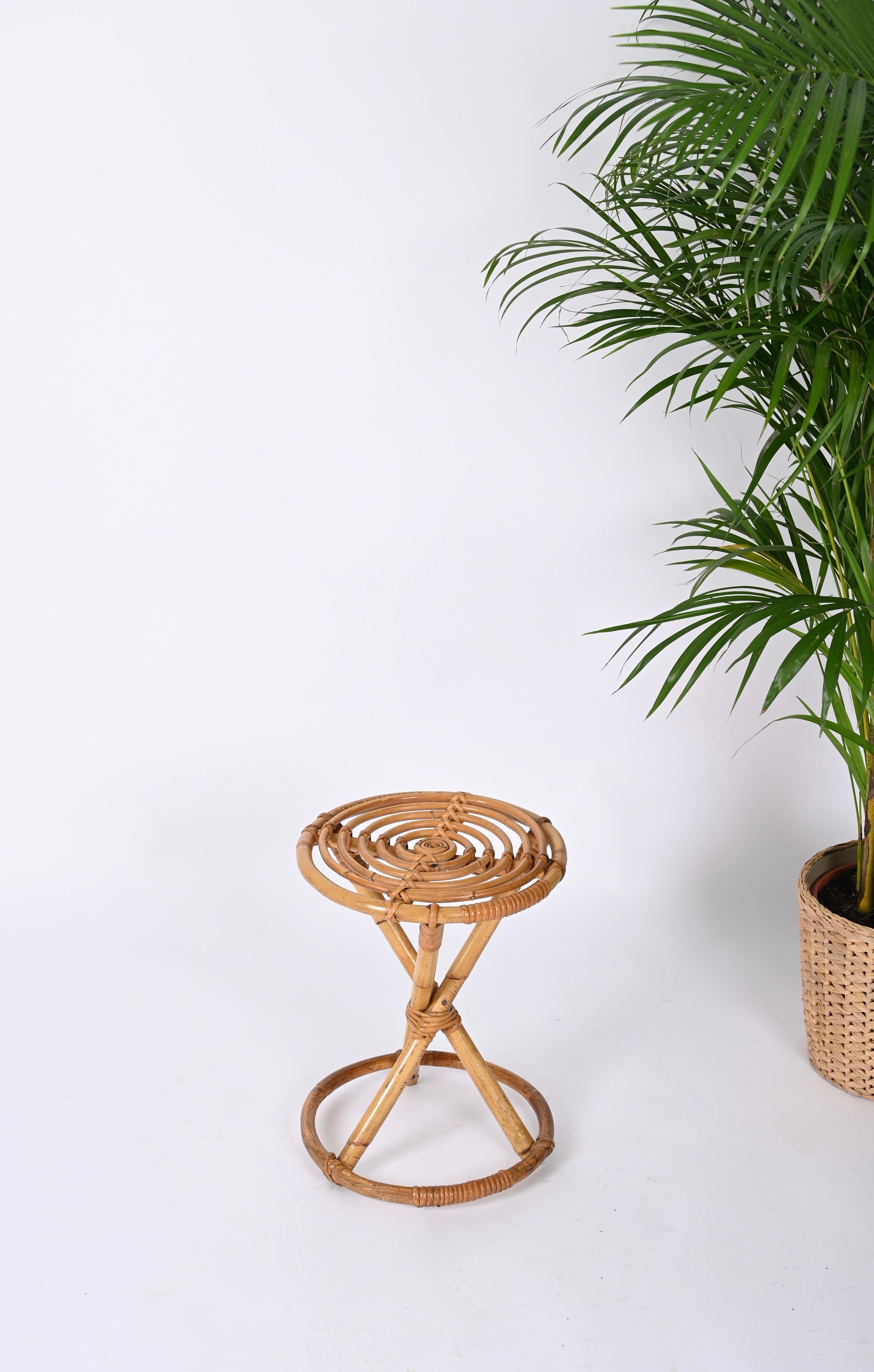 Lovely Mid-Century rattan and bamboo round stool. This amazing piece was produced in Italy during 1960s.

The stool features a round base in curved bamboo, three straight legs and a gorgeous round seat decorated inside by spiral-shaped bamboo kept