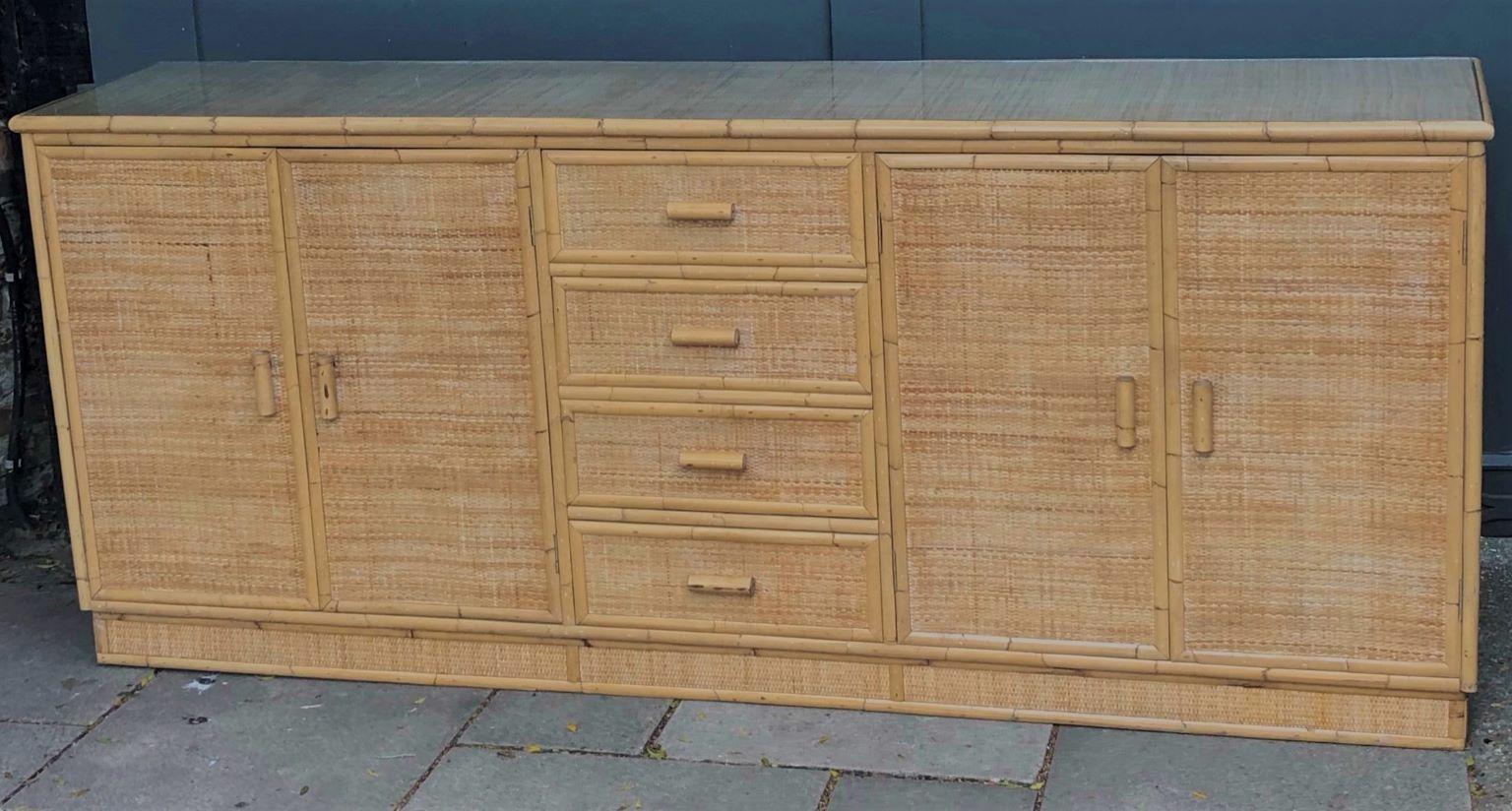 Mid Century rattan and bamboo sideboard, Italy, 1970s

Large and impressive sideboard, wooden structure with rattan and cane detail, covered in close weave matting, also with cane handles.

Four drawers in the middle, with a two door cupboard