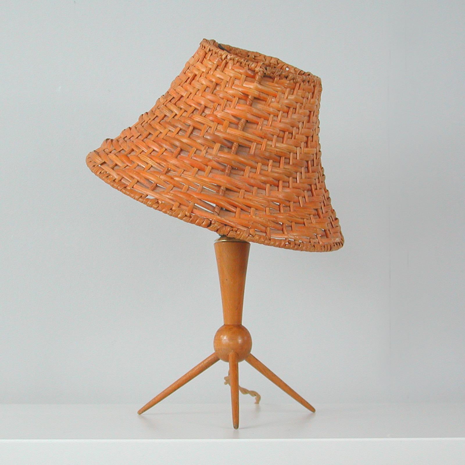 This unusual rattan or wicker table lamp was designed and manufactured in Sweden in the 1950s. It features a minimalist birch tripod base with a clip-on rattan lampshade. The lampshade can be moved in different directions.

Good original condition
