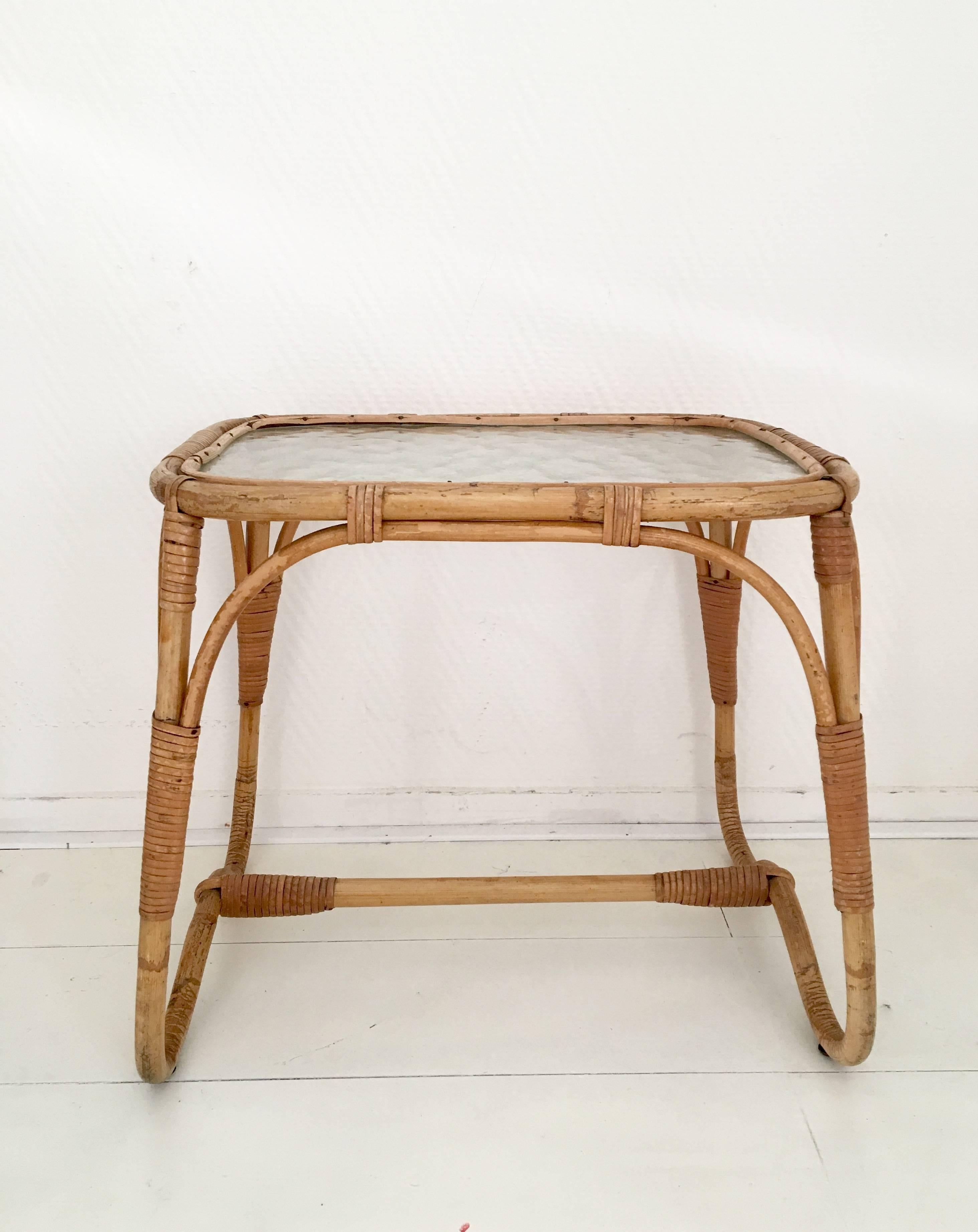 Cette petite table basse ou d'appoint a été conçue et fabriquée aux Pays-Bas, vers les années 1960. Il présente une base en rotin/bambou et un plateau en verre. La table est en très bon état et ne présente que des signes minimes d'âge et