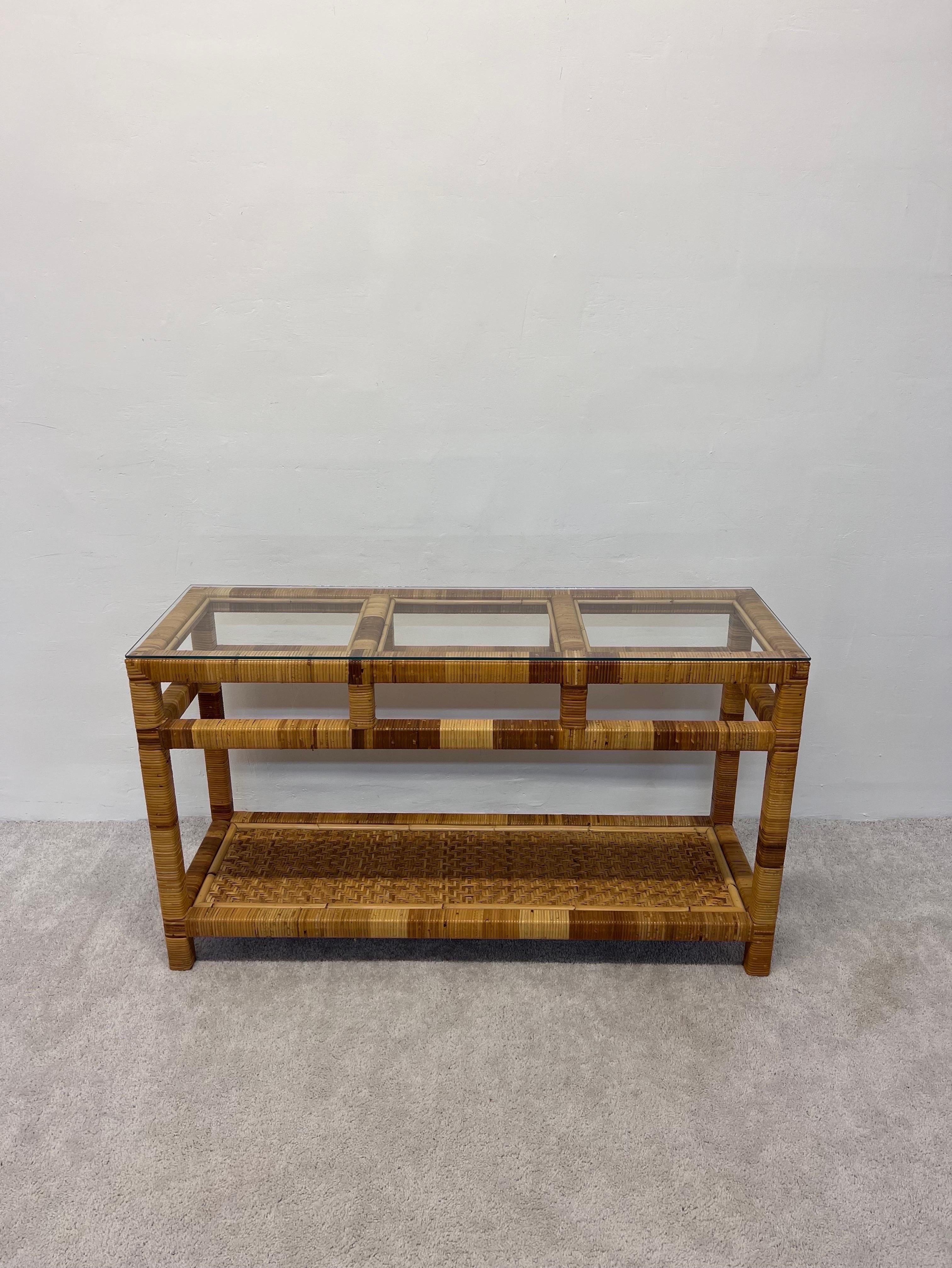 Woven rattan console table with glass top from the 1970s. The lower shelf has a rattan chevron pattern and top shelf is 1/4