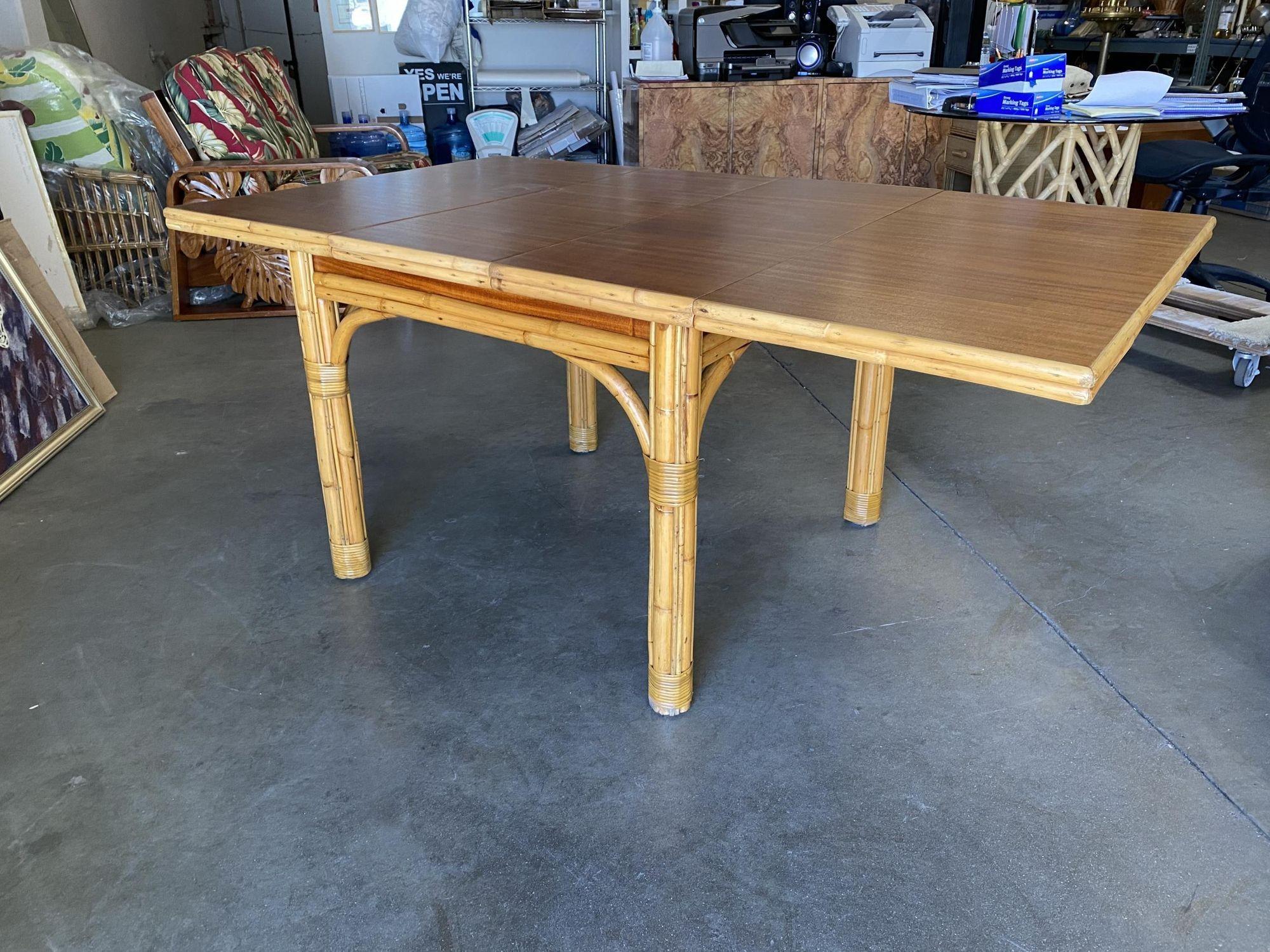 Mid-century six-eight person rattan dining table with pole rattan base and a solid mahogany table.

The large rattan dining table comes with three pole rattan legs and a solid mahogany table complete with two leaves that pull out / pull-out from