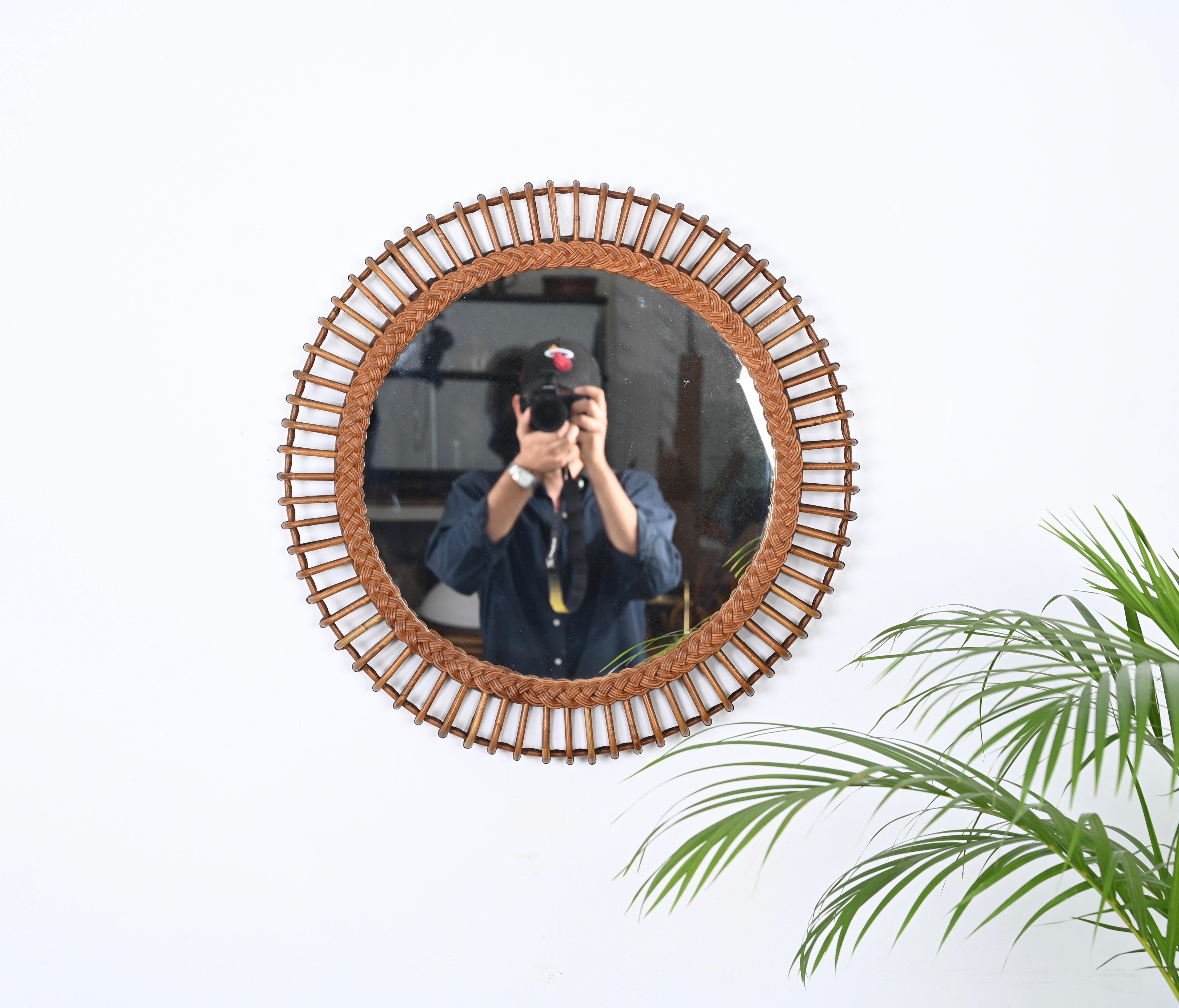 Marvelous mid-century French Riviera style round mirror in Rattan and Bamboo. This beautiful piece was produced in in Italy during the 1960s. 

This stunning mirror has a double frame idecorated by stunning curved rattan beams and wicker. The