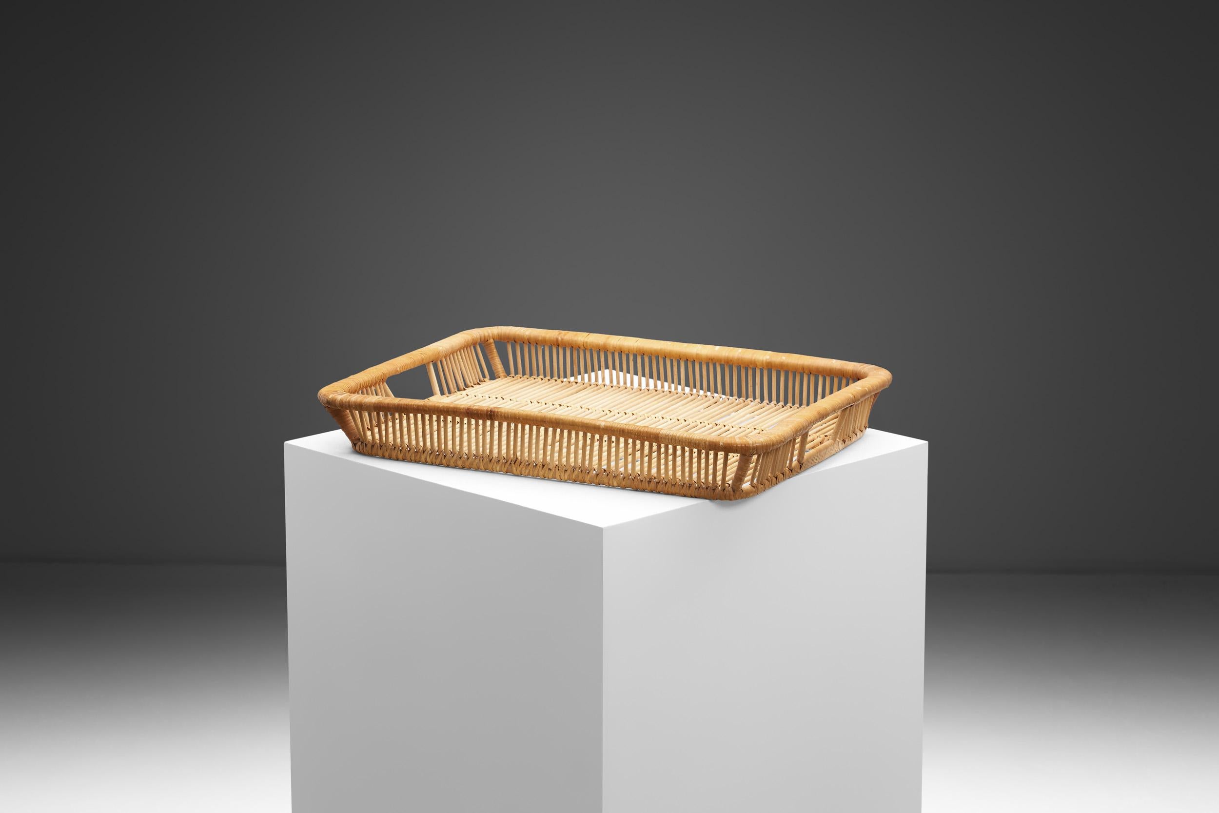 This lovely and stylish rattan tray was designed and made by Artek in Finland during the 1960s. It is hand woven from cane and rattan, and exemplifies Artek's commitment to blending functionality, craftsmanship, and aesthetics.

Artek, the renowned