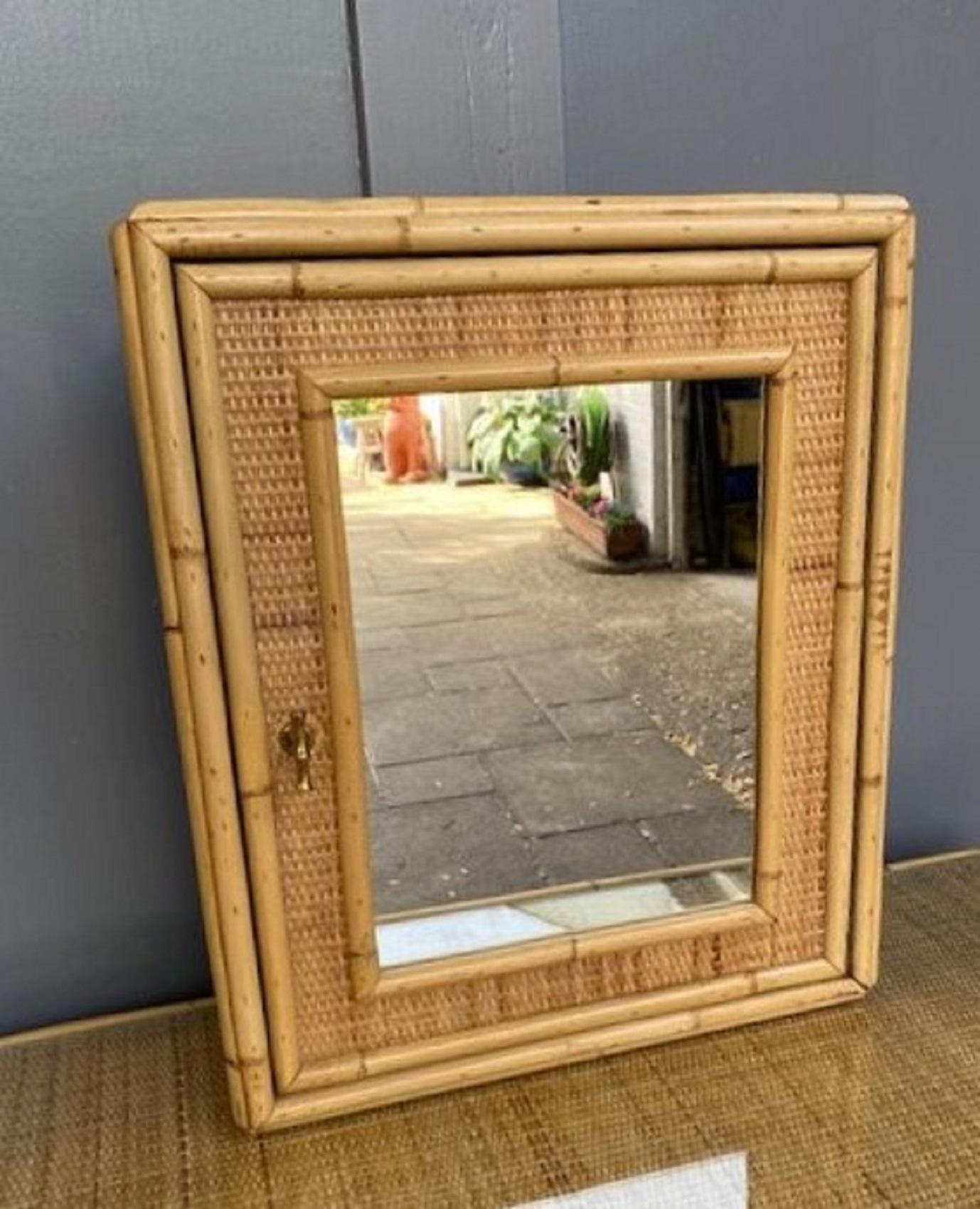 Mid Century Rattan Bathroom Wall Cabinet / Vanity, French 1970s 

Beautiful rattan bathroom wall cabinet. Wooden structure with rattan and cane detail, covered in close weave matting, mirrored door with brass faux bamboo handle. Single interior