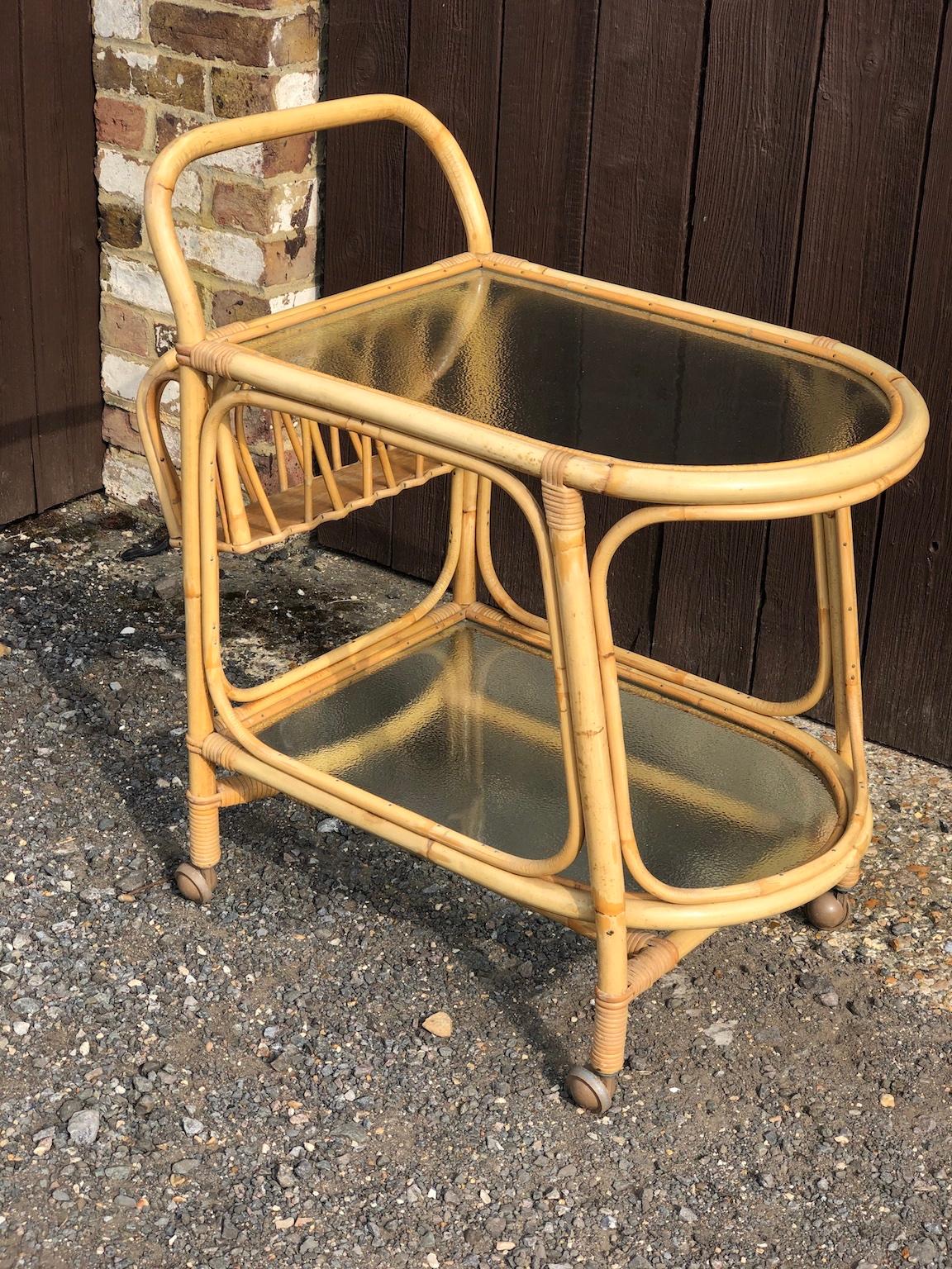 Mid Century Rattan / Cane Drinks Trolley by Angraves, circa 1970

A beautiful vintage rattan drinks trolley / bar cart by ‘Angraves’ of Leicester. Two tiers with glass shelves, 
bottle holder (4 bottles) on 4 x metal castors.
This trolley is in