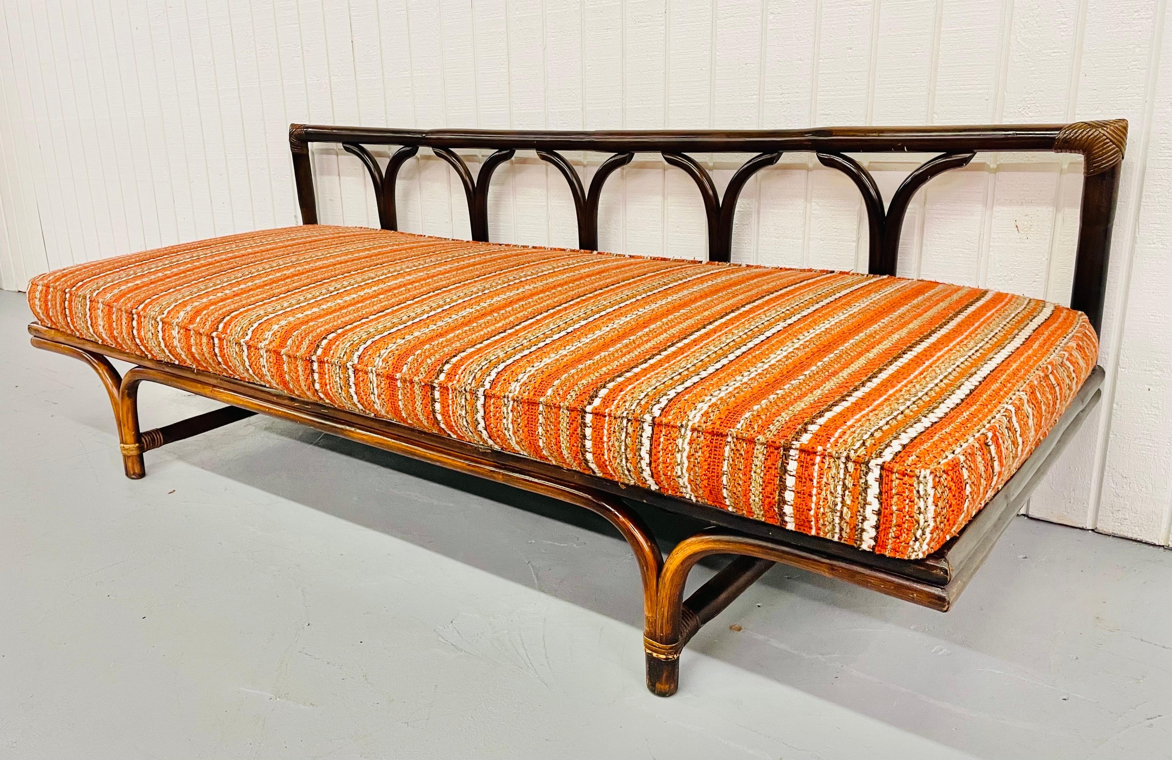 This is an exceptional rare mid-century rattan day bed. With the original orange cushion in excellent condition. A true statement piece!