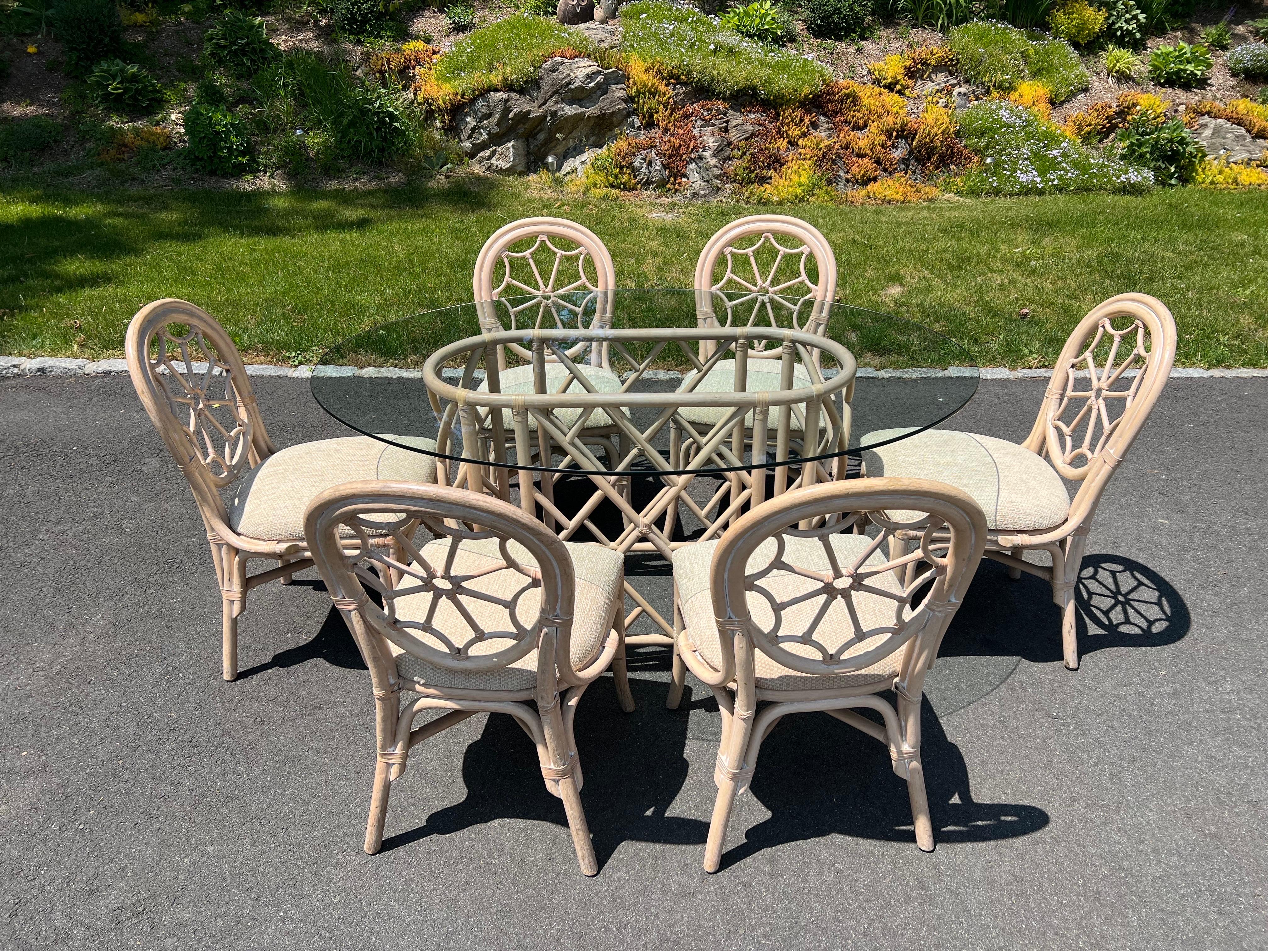 Mid Century Rattan Dining Set with Six Chairs. Amazing cobweb designed back to these sculptural chairs. Covered in a neutral oatmeal chenille. Large oval glass top sits above the intricate chinoiserie designed oval base. The existing glass top is a