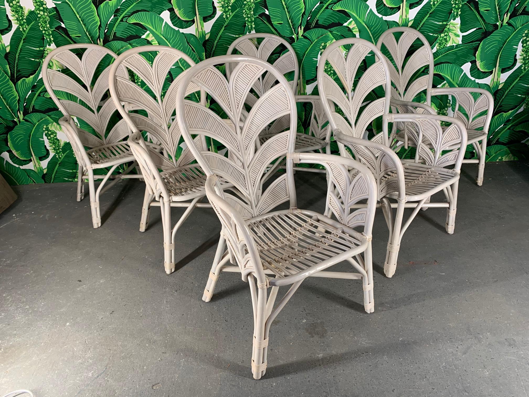 Midcentury rattan arm chairs feature sculptural palm frond motif for a touch of vintage Palm Beach style in any decor. No makers mark other than Made in Philippines tag. Good vintage condition with minor abrasions consistent with age.