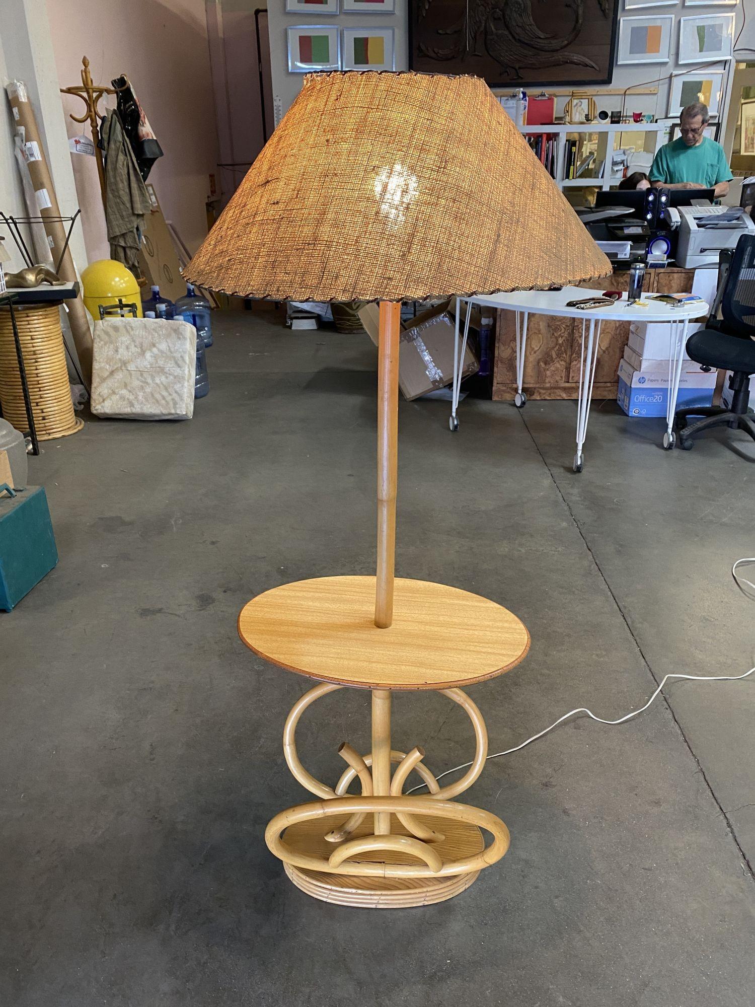 Rattan pole lamp featuring a decorative single rattan pole centered around a drink side table fixed to a mahogany and rattan oval base. This lamp is perfect for Mid Century lounge or living room. 
 
Circa 1950
 
We only purchase and sell only