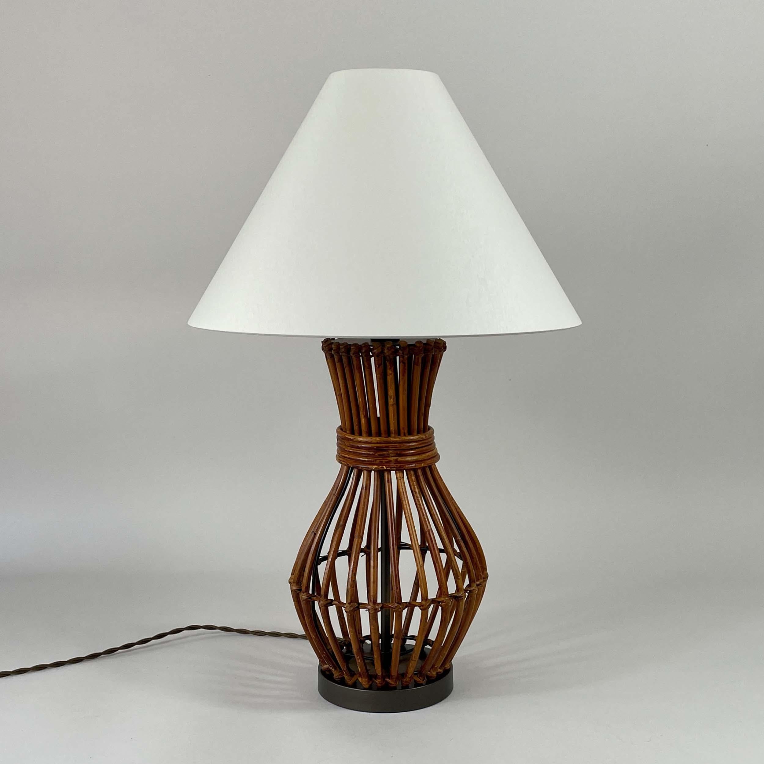 Esta lámpara de sobremesa de mediados de siglo fue diseñada y fabricada en Franke en la década de 1960.

La lámpara tiene una escultural base de ratán con la clásica forma de reloj de arena de mediados de siglo, hábilmente construida con listones