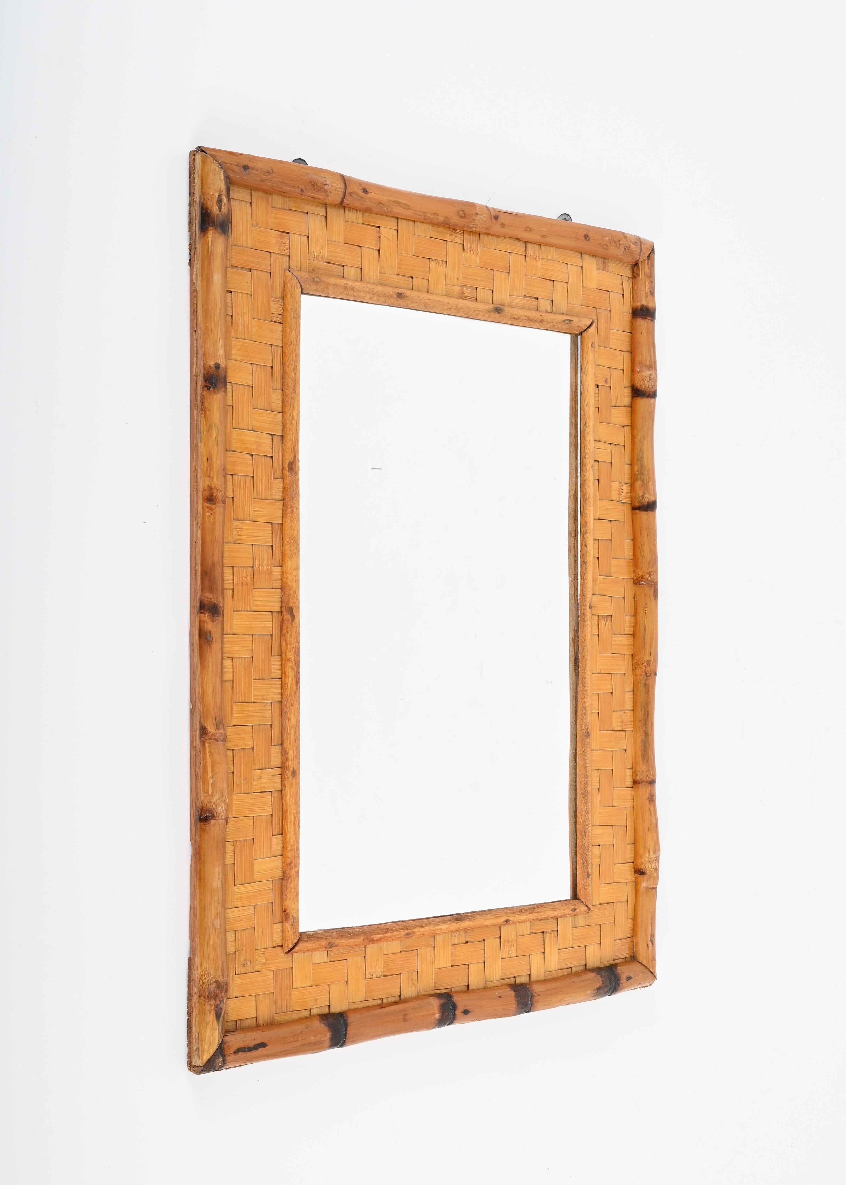 Astonishing Mid-Century rectangular mirror made in bamboo cane and woven rattan. This fantastic piece was designed in Italy during the 1960s.

This mirror is unique thanks to its stunning double frame,  made of a larger external bamboo frame and a