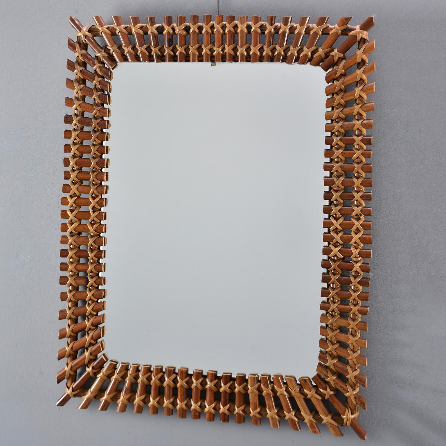 Rectangular mirror of unknown origins found in Italy features a frame made of bamboo reeds with contrasting hand-tied caning reed, circa 1960s. Unknown maker. Other mirrors with similarly styled frames available at time of this posting.