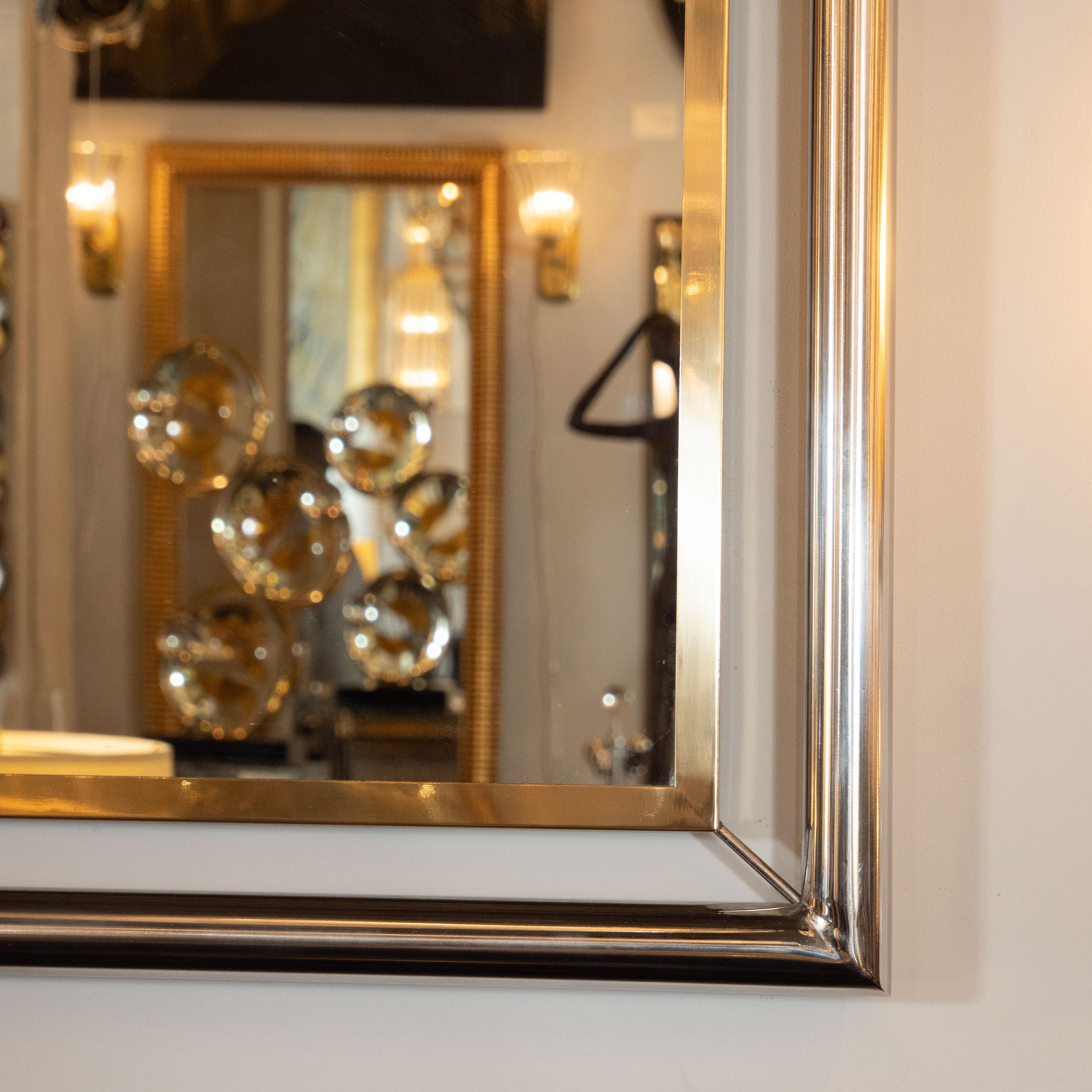 This sophisticated and striking floating wall mirror was realized in the United States, circa 1970. It features a rectangular polished brass frame that is surrounded by a larger frame in lustrous tubular chrome. The inner and outer frames are