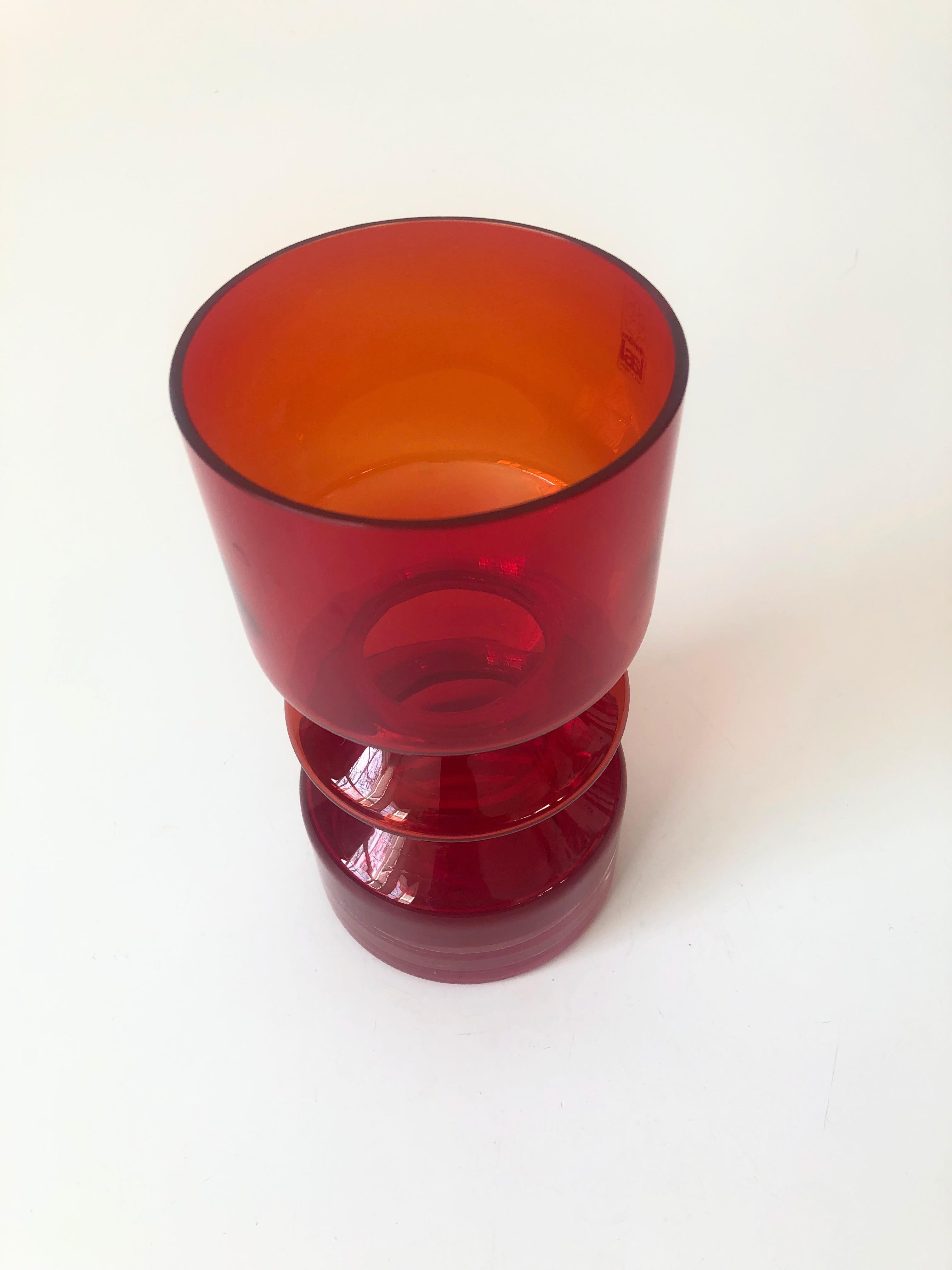 A beautiful mid-century Finnish glass vase. Designed by Tamara Aladin for Riihimaen Lasi in the 1960s. Vibrant red color to glass and cylinder shape with a hooped center. Design no. 1472. The original sticker is attached. 
 