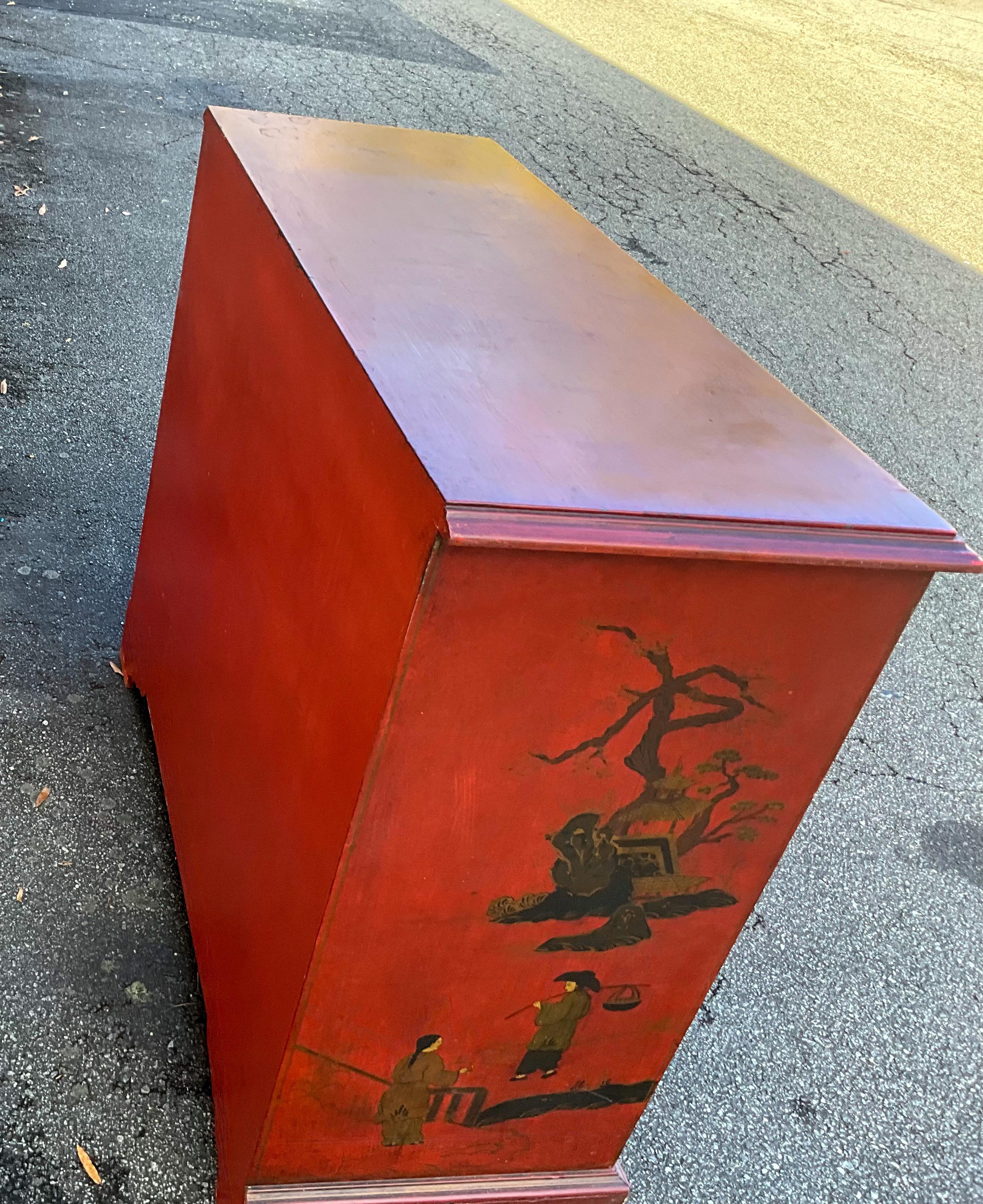 This is a mid-century red chinoiserie cabinet with Georgian styling. It opens to reveal a single shelf storage. It has general age wear.